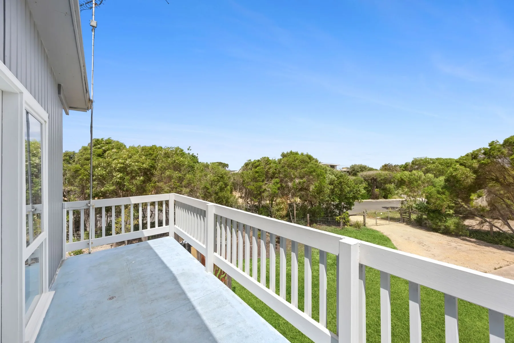 A raised outdoor deck overlooks trees and a sandy path.