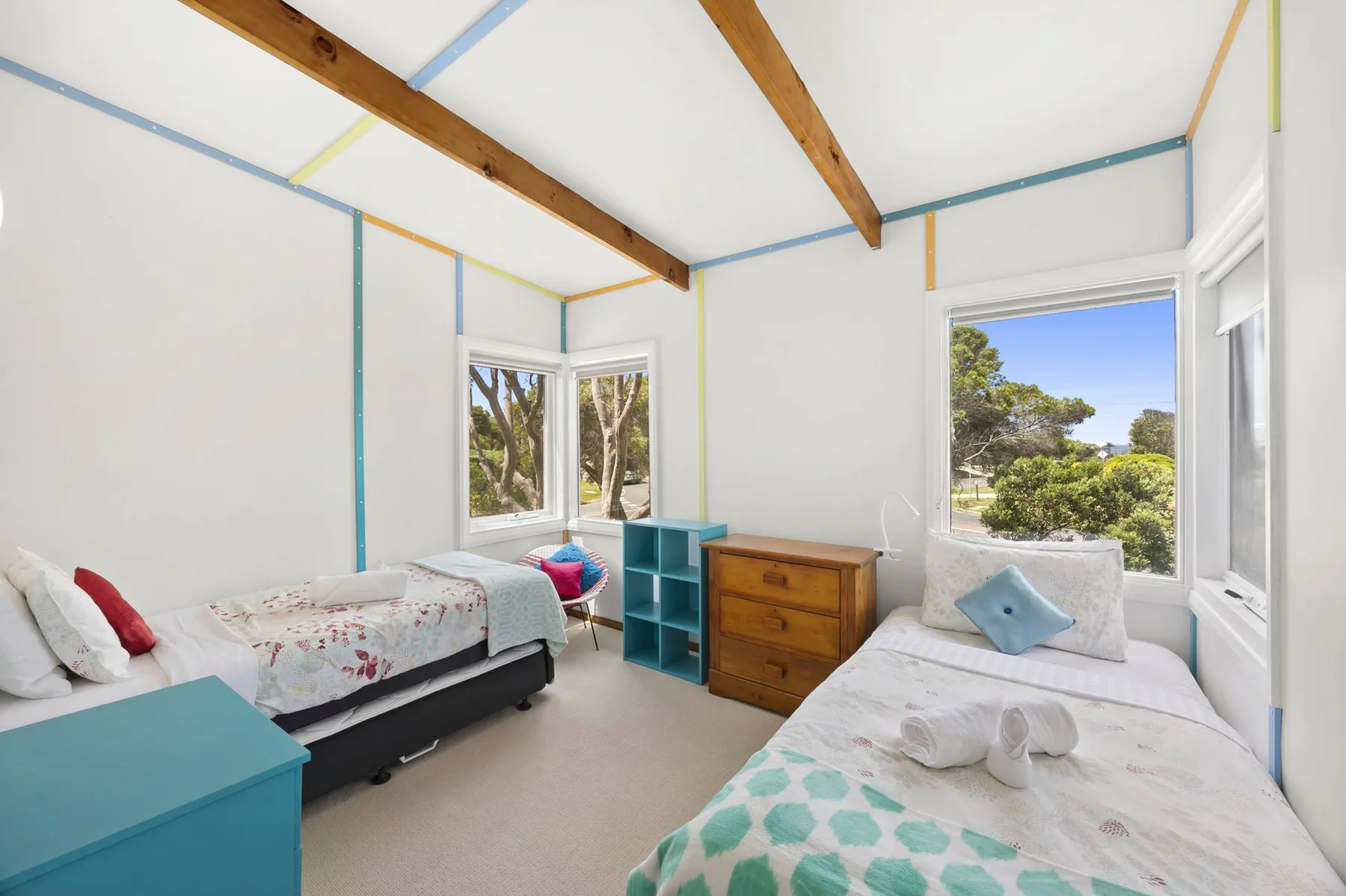 A bright bedroom with two beds and large windows.