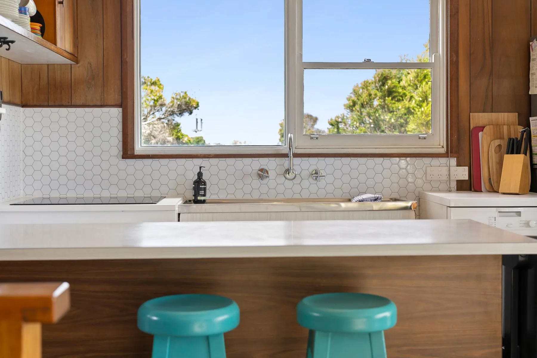 Una isla de cocina con asientos está debajo de una ventana grande.