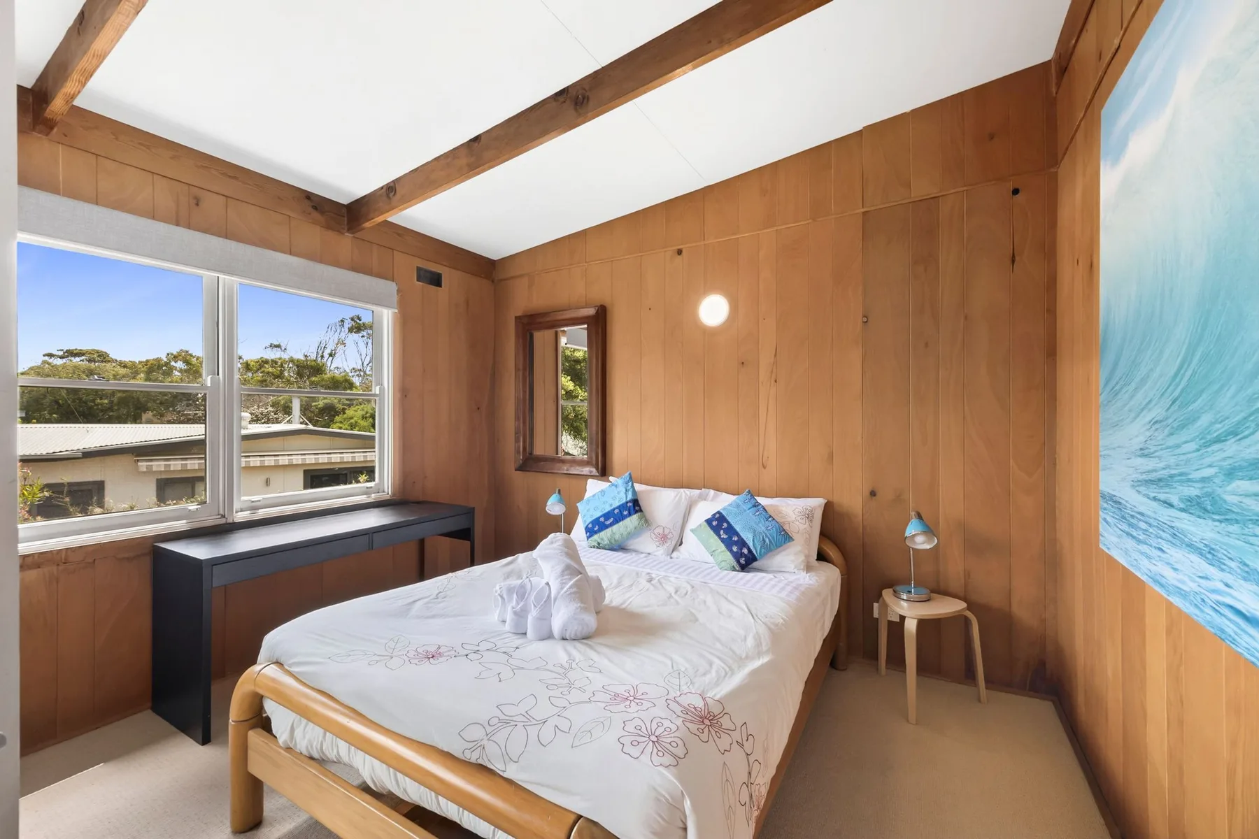 A wood-paneled bedroom with a bed beneath exposed ceiling beams.