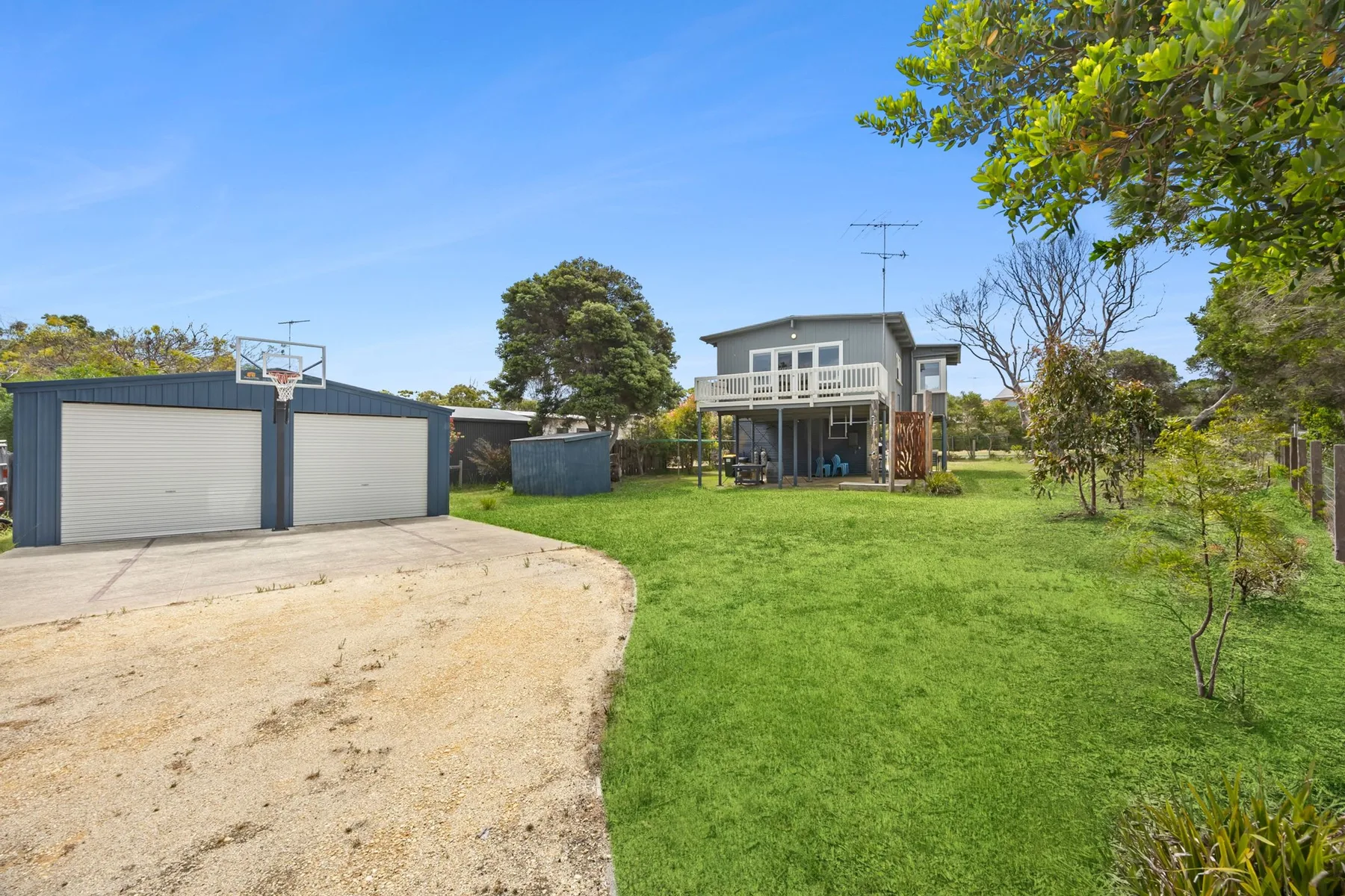 A two-story house stands beyond a broad green lawn and driveway.