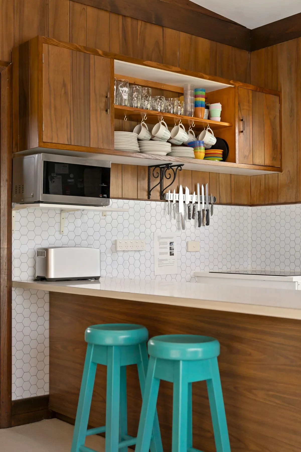 A kitchen with wooden cabinets and turquoise stools at the counter.