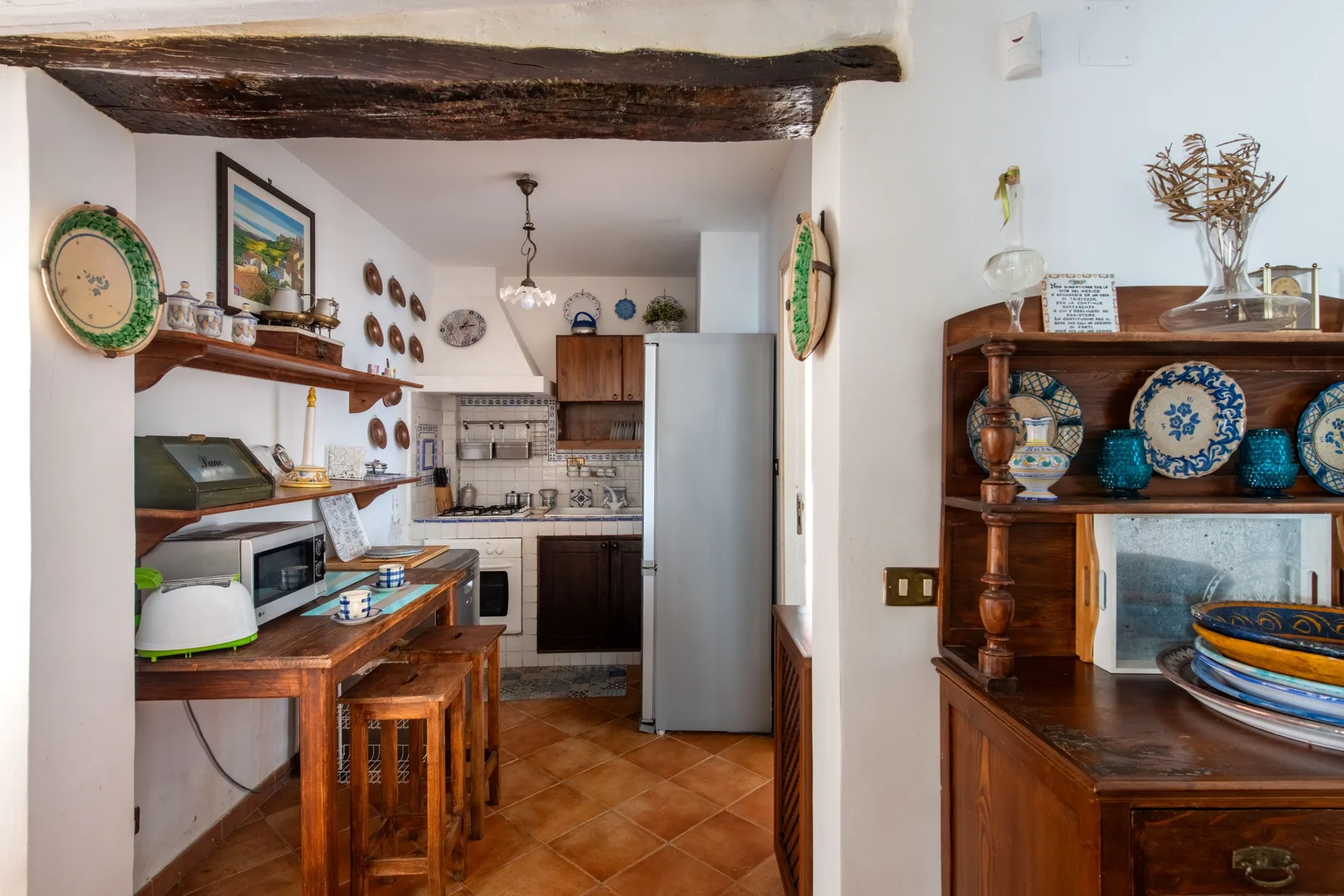 A compact kitchen with wooden furnishings and decorative ceramics on display.