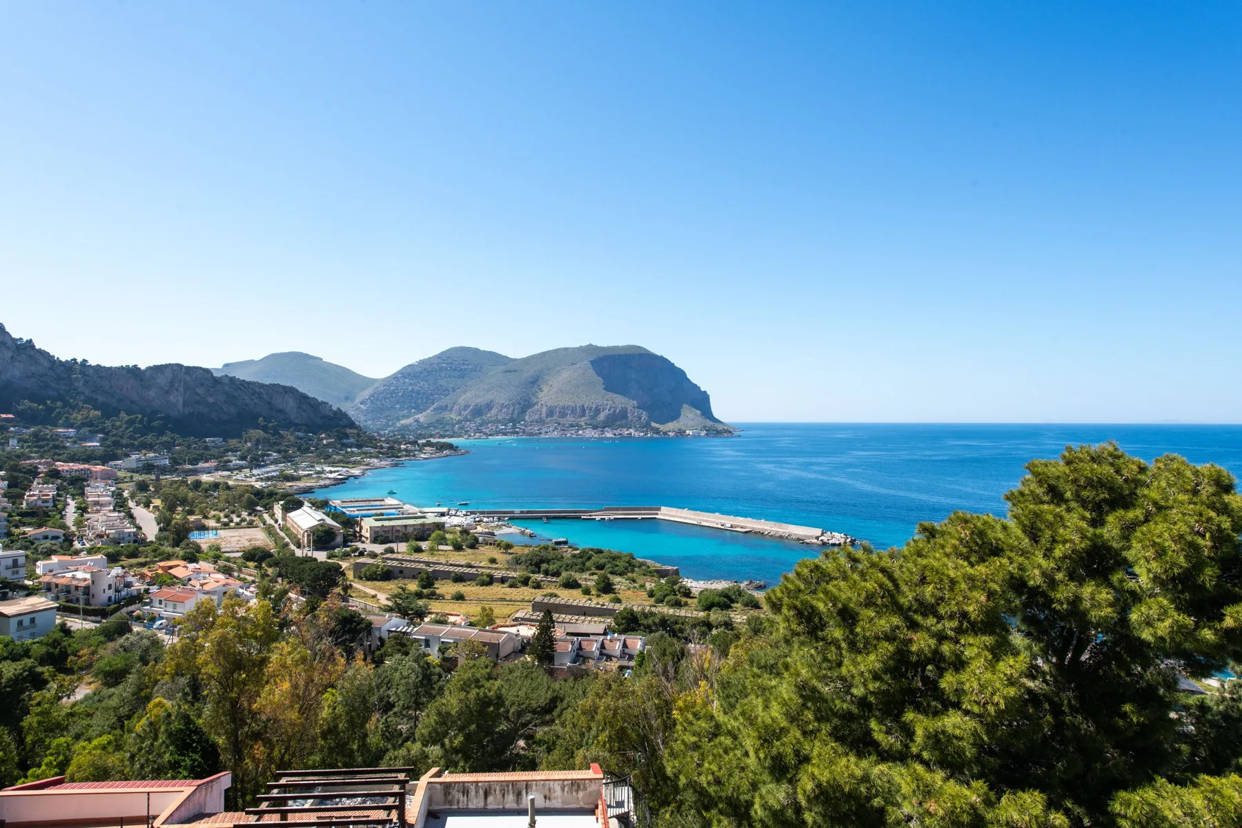 A coastal bay and surrounding mountains are visible beyond a hillside town.