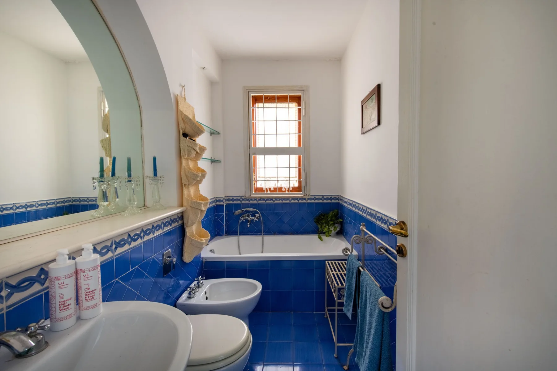 A tiled bathroom with a bathtub, sink, and window.