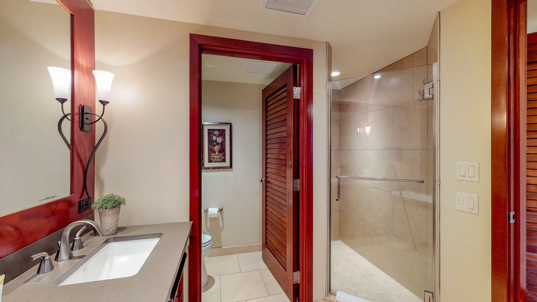 A bathroom vanity and sink beside a glass-enclosed shower and open doorway.