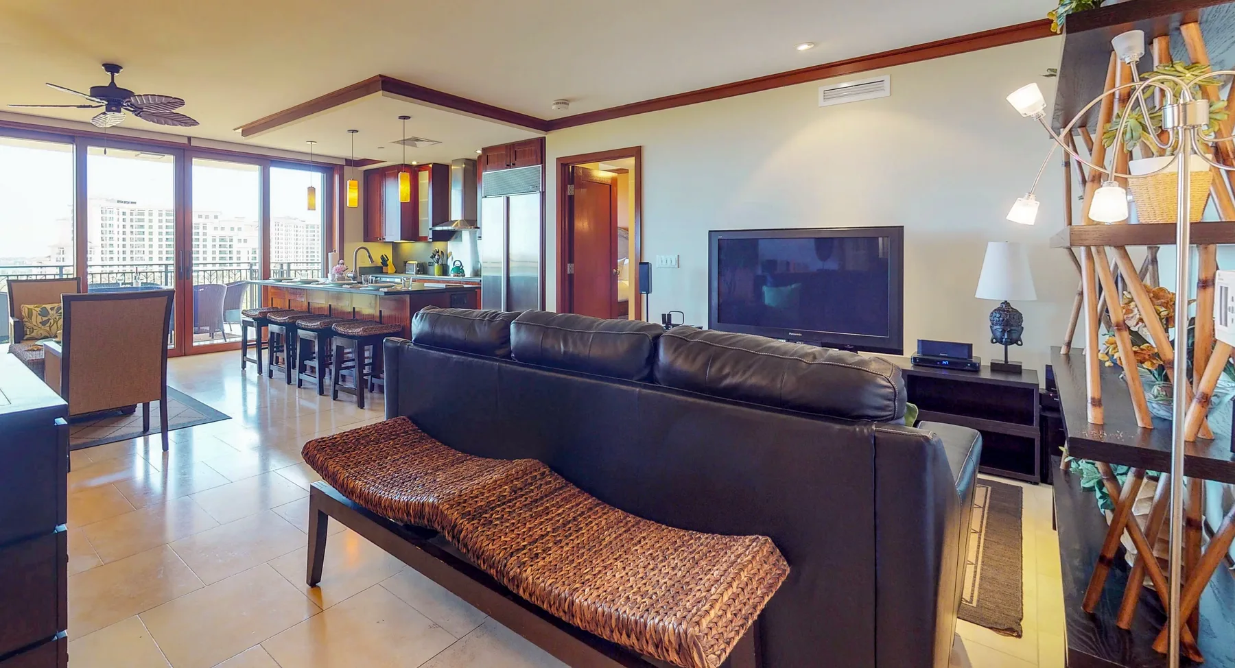 A living room with dark seating, a television, and a dining area by the windows.