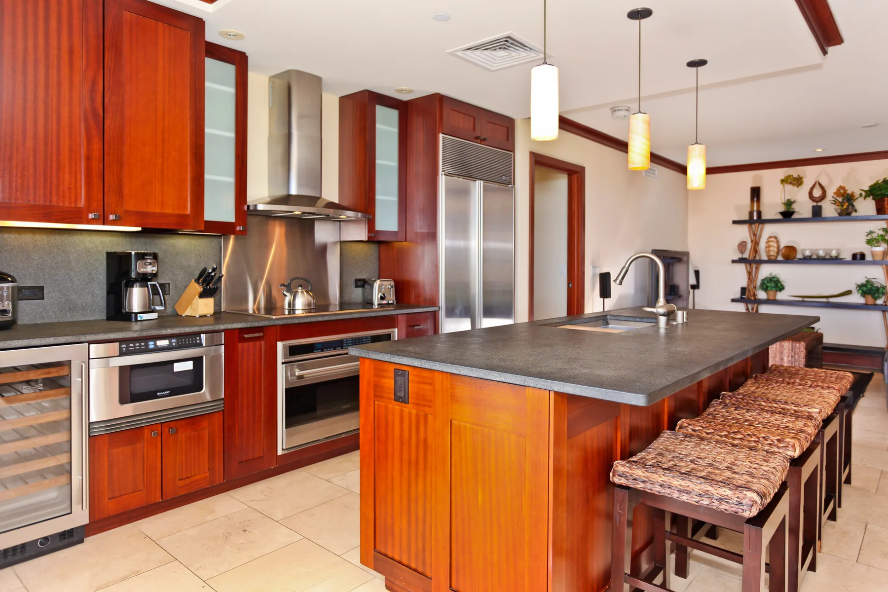 Una cocina moderna con gabinetes de madera rojiza, electrodomésticos de acero inoxidable y una isla amplia.