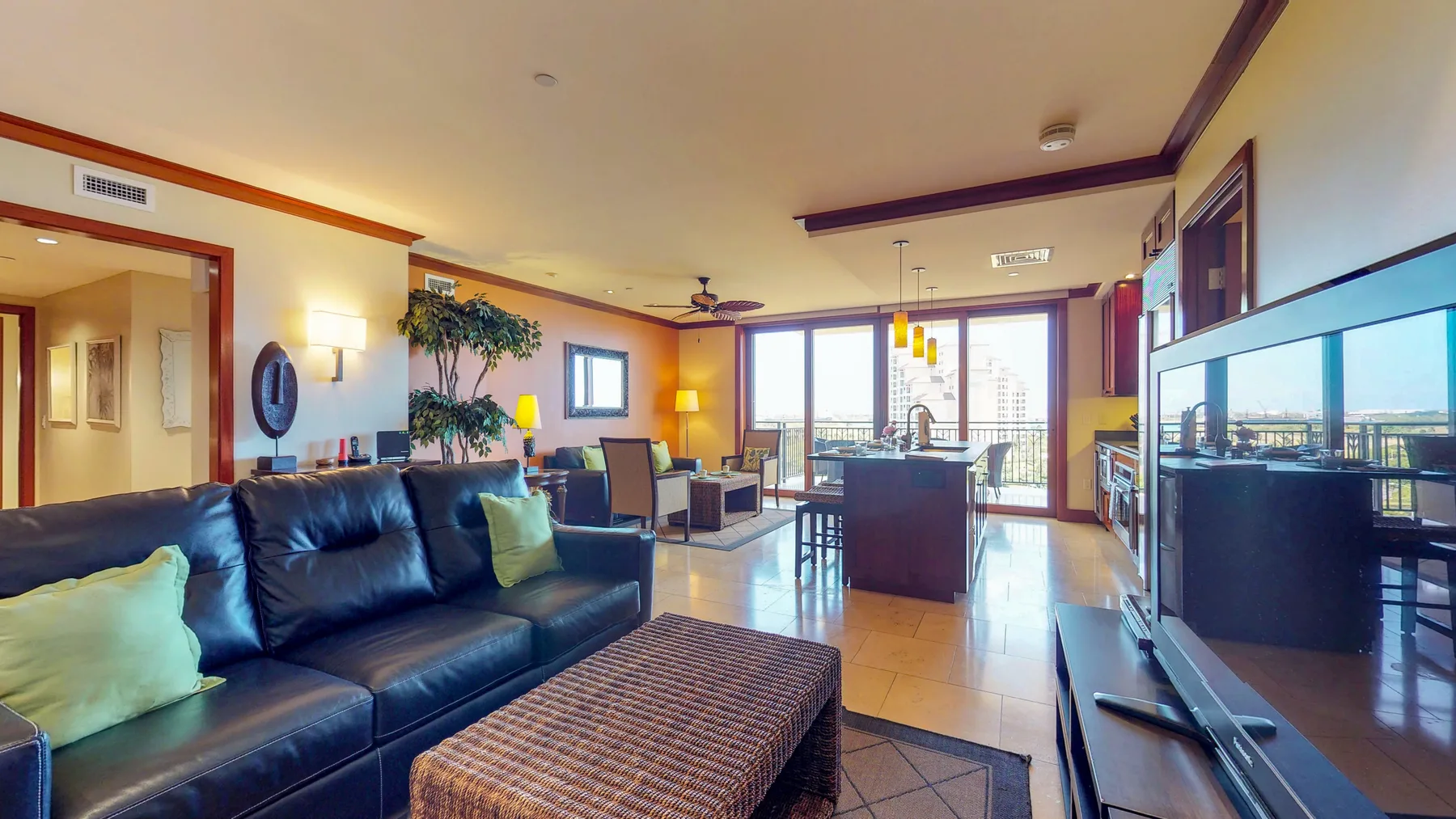 A living room with a dark sofa and large windows opening onto a balcony.
