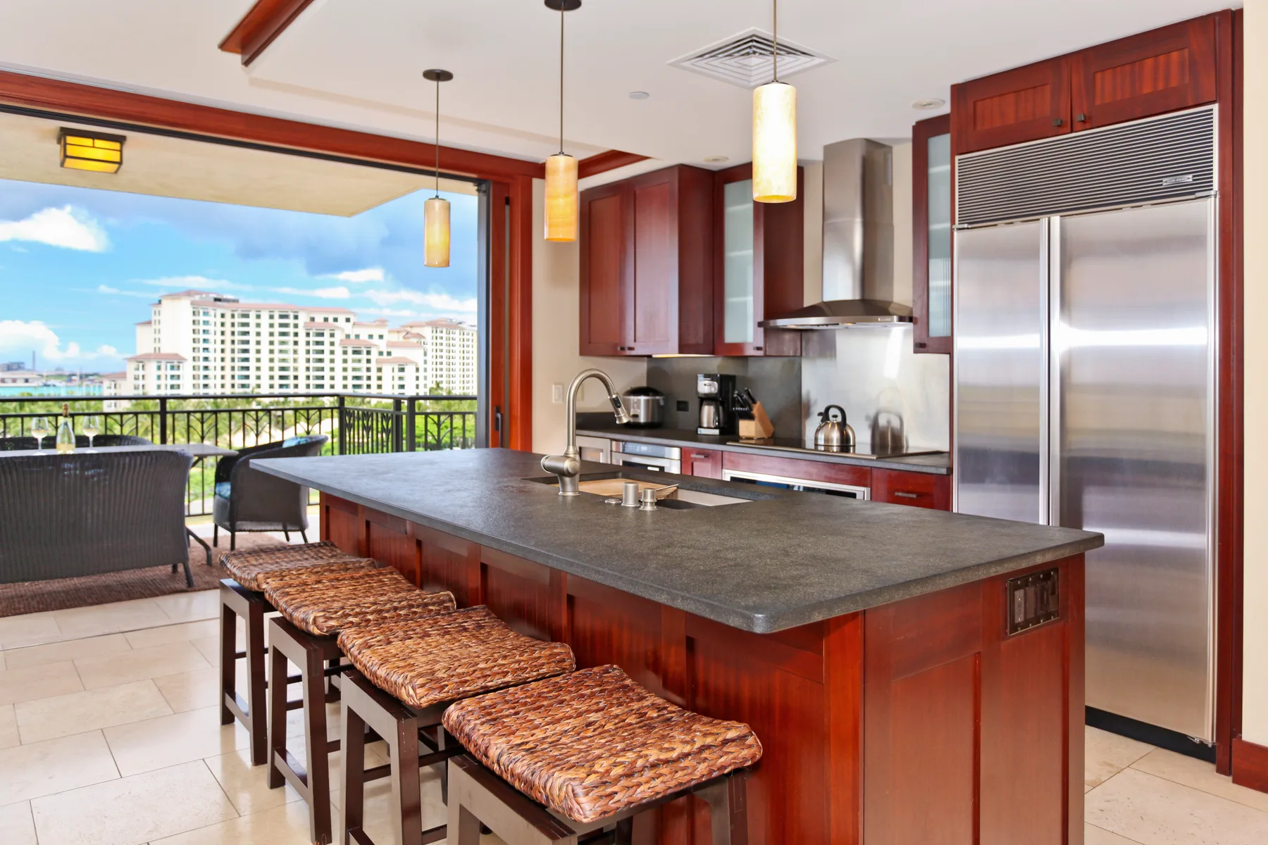 A modern kitchen with a large island and bar seating opens onto a balcony.