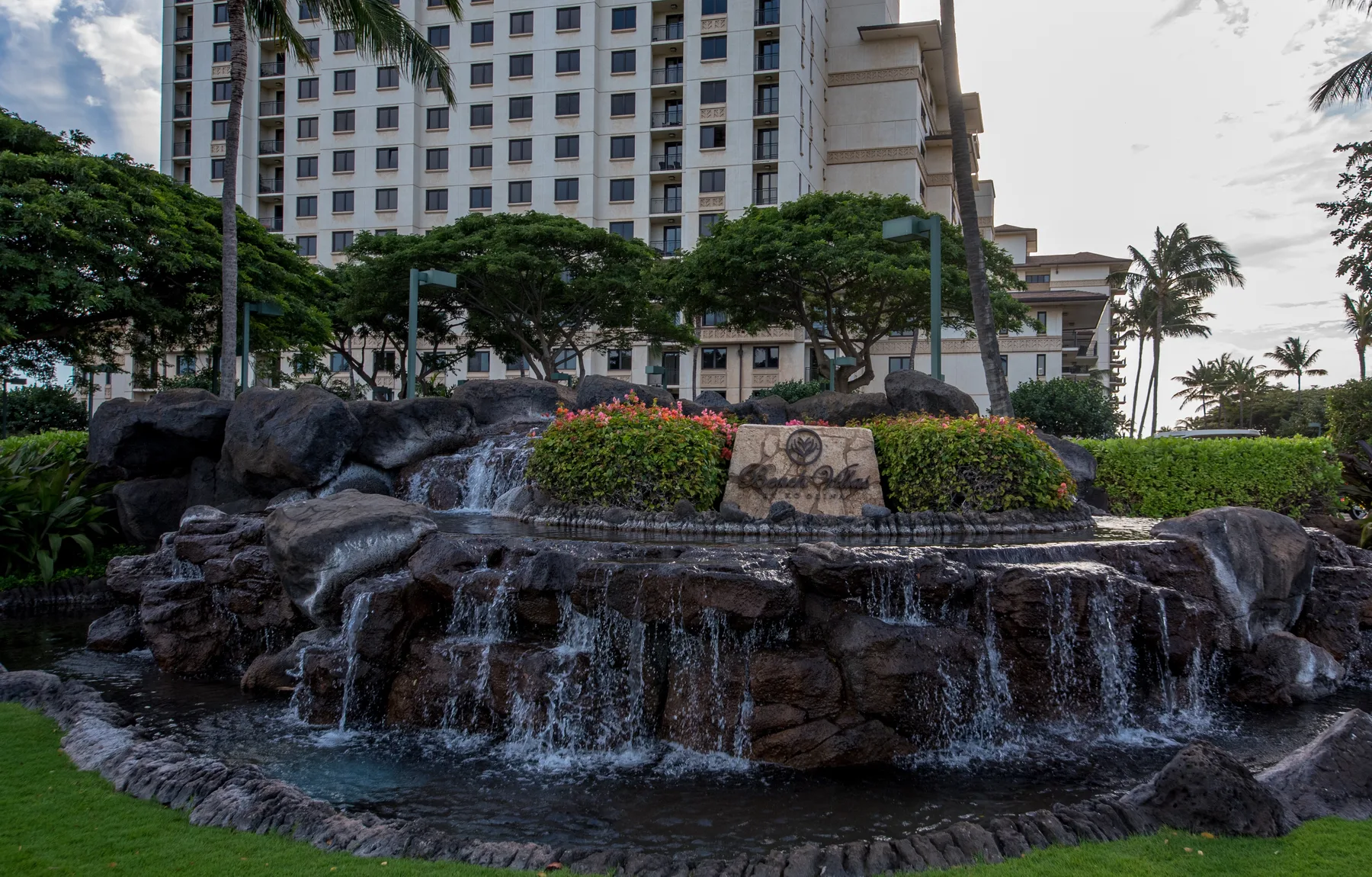A landscaped outdoor waterfall sits in front of a tall building.