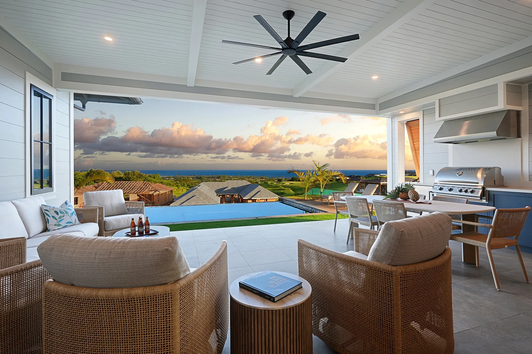 A covered outdoor patio with seating, a dining area, and a pool overlooking the landscape.