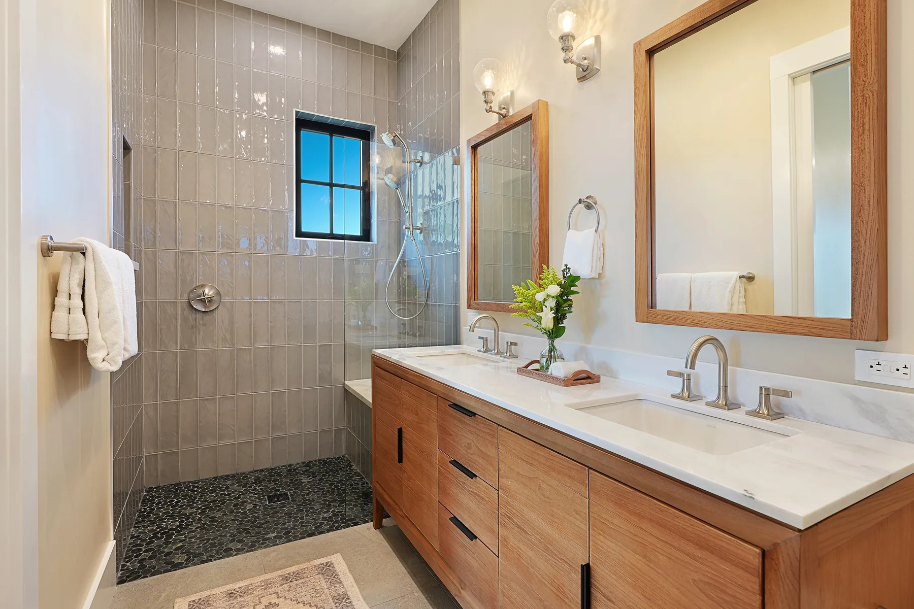 A bathroom with a tiled shower area and a long vanity with a mirror.