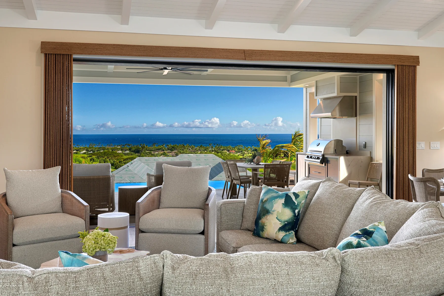 A furnished living room opens onto a patio with a view of the ocean.