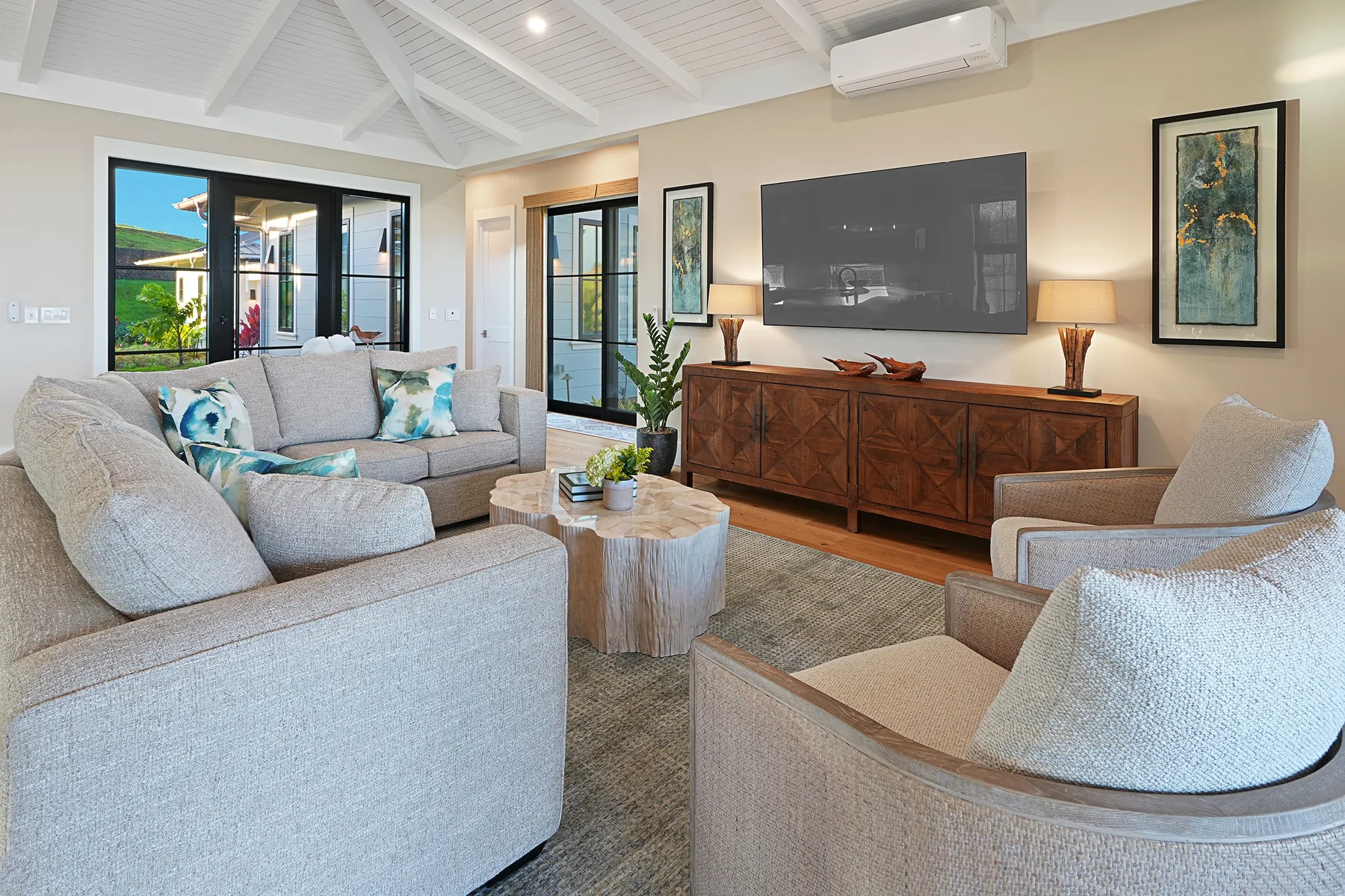 A bright living room with seating arranged around a coffee table and television.