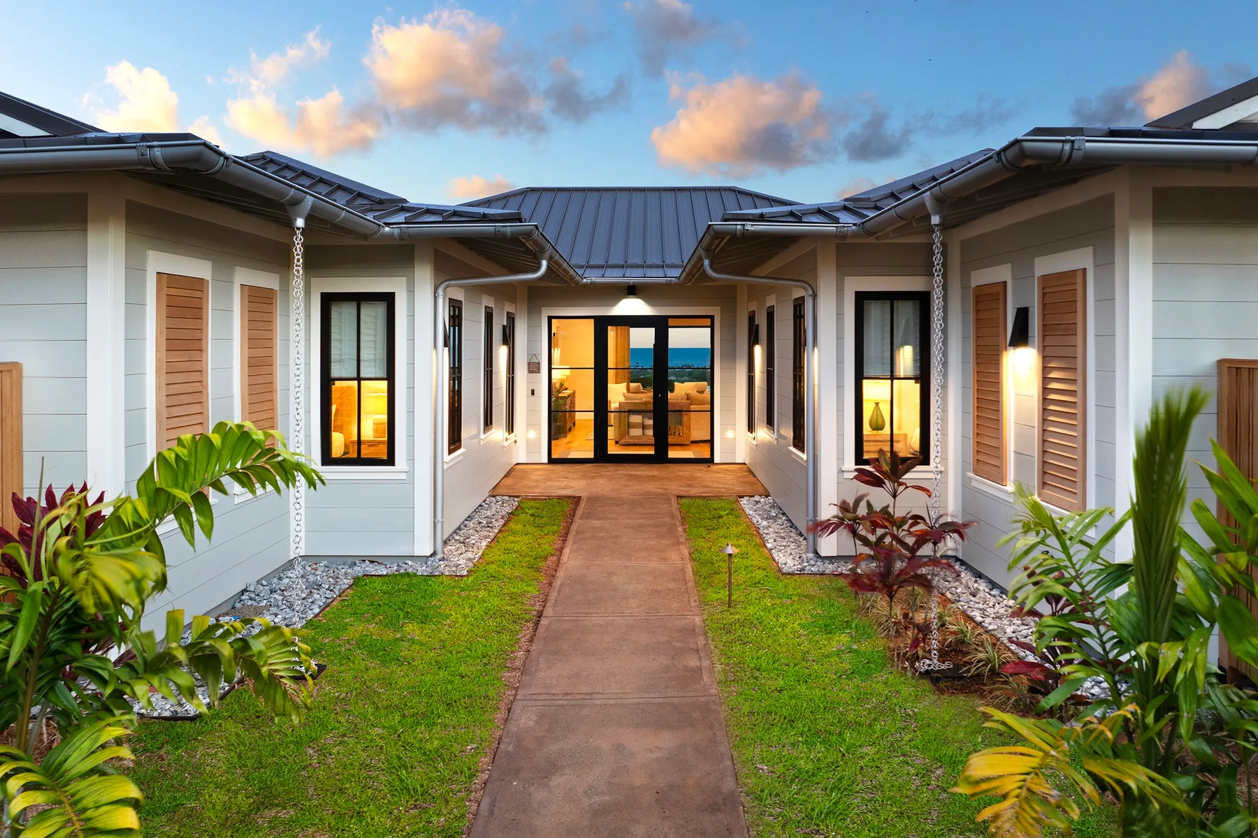 A paved walkway leads through a landscaped courtyard to a modern building entrance.