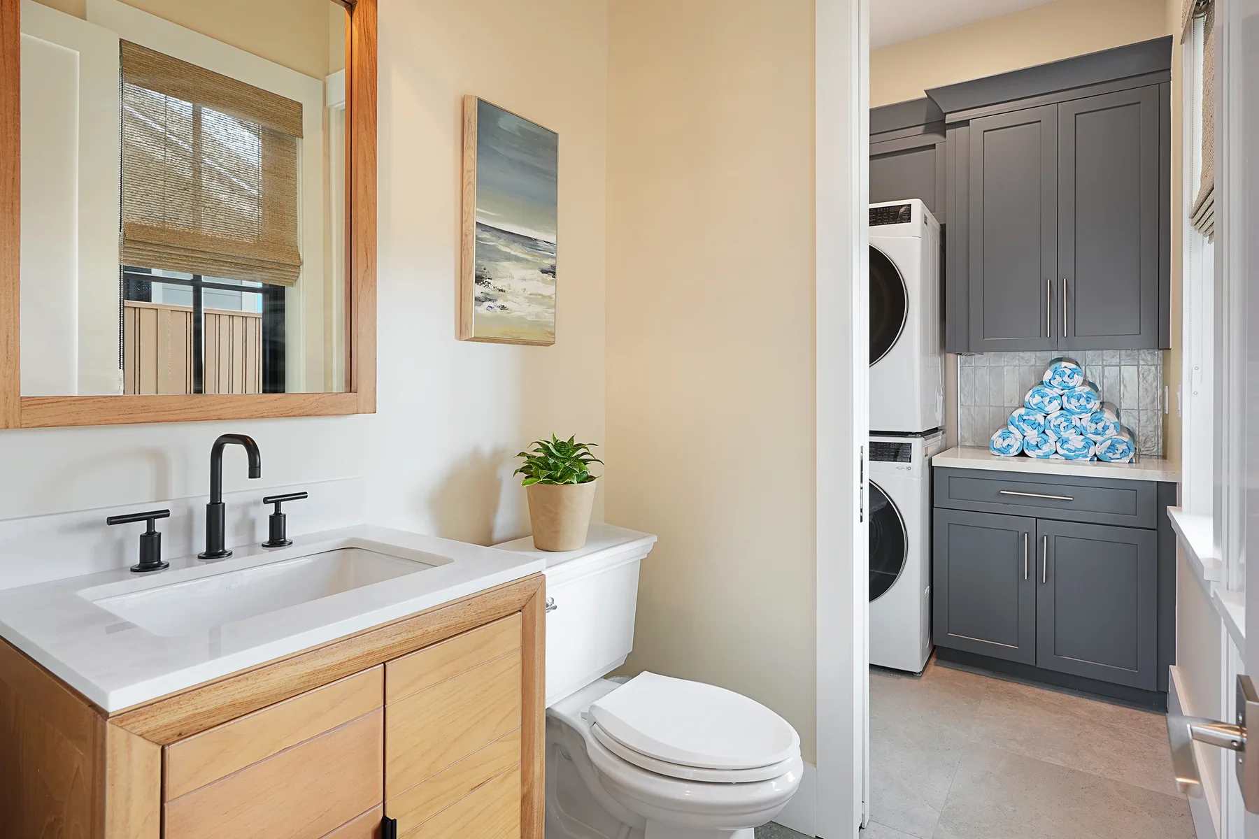 A bathroom vanity and toilet beside a laundry area with dark cabinets.
