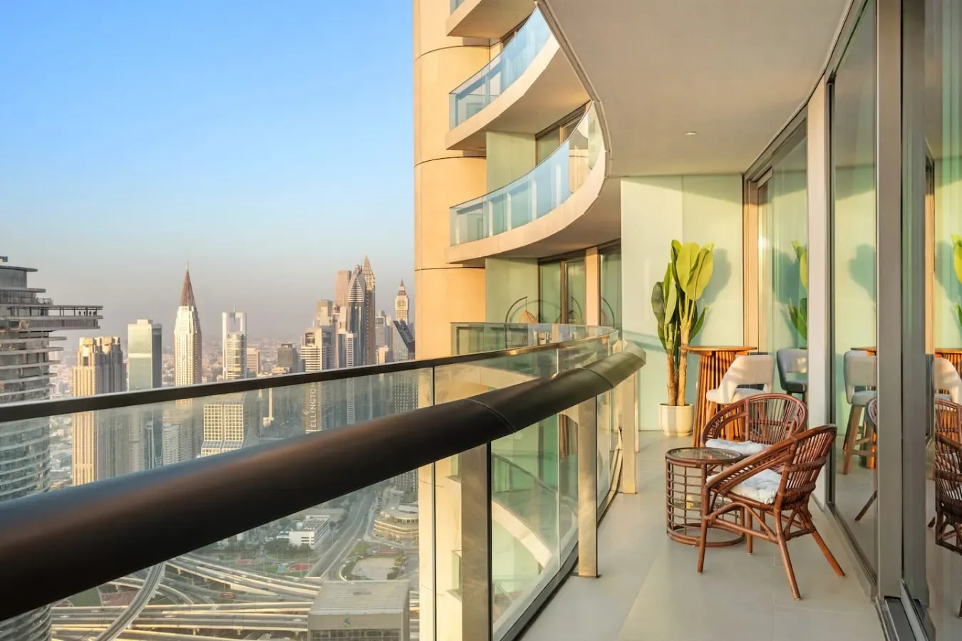 A balcony with seating overlooks a city skyline through a glass railing.