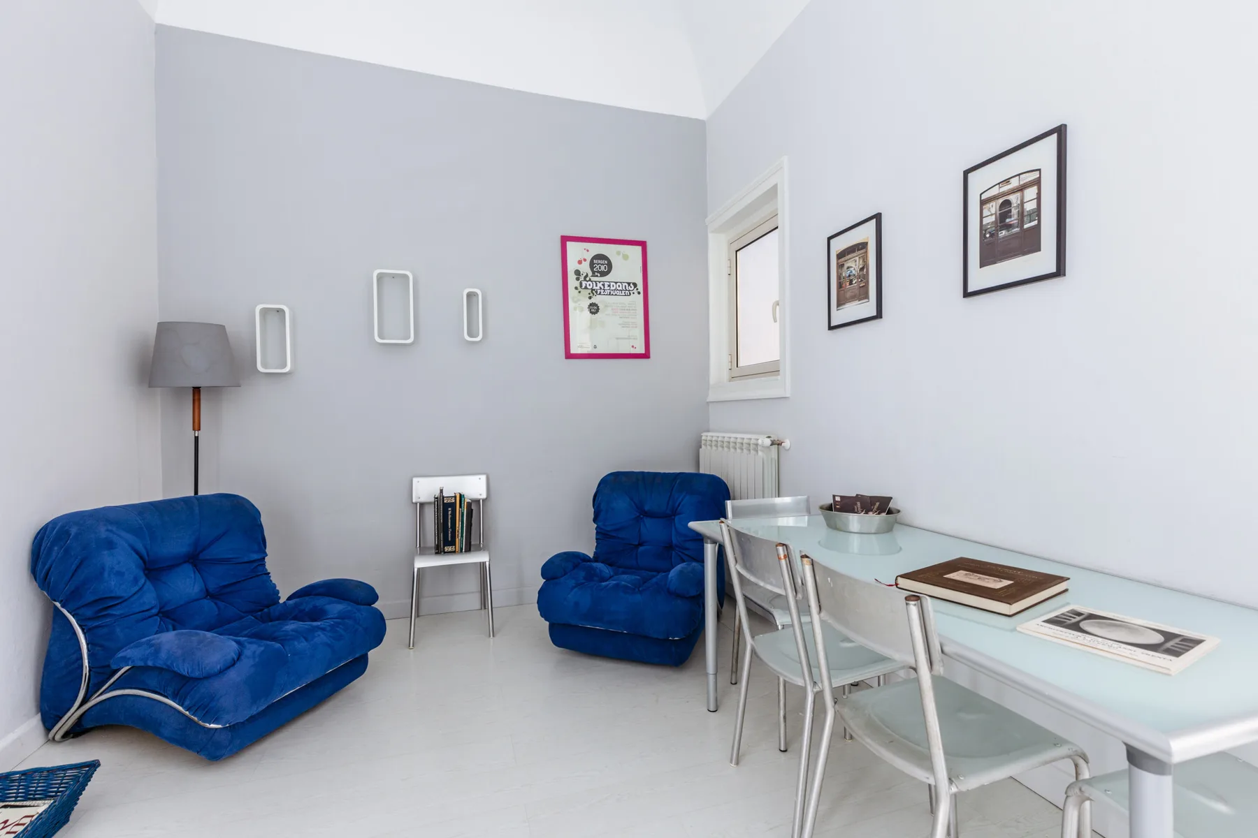 A bright sitting area with blue seating and a glass dining table.