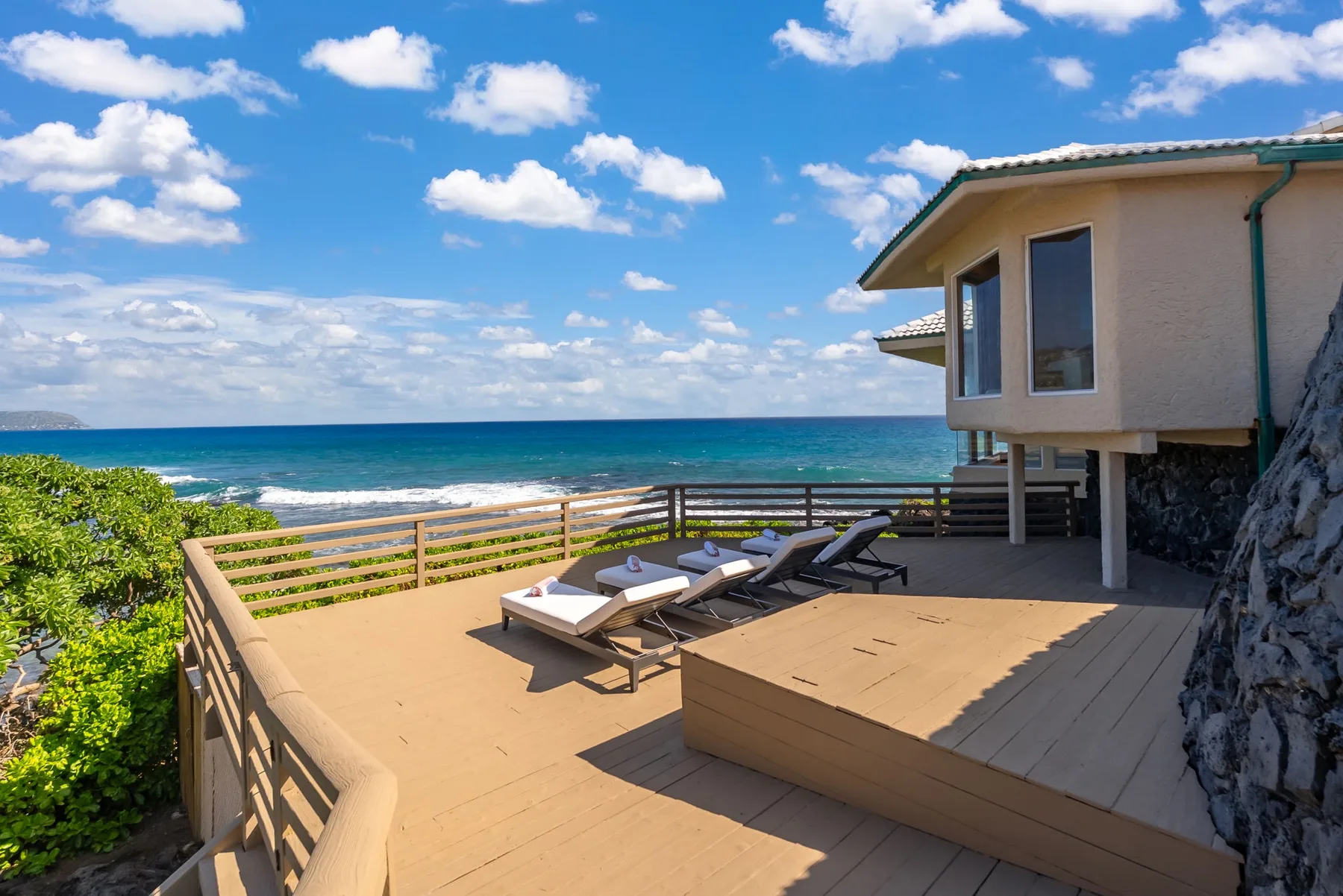 A seaside deck with lounge seating overlooks the ocean.