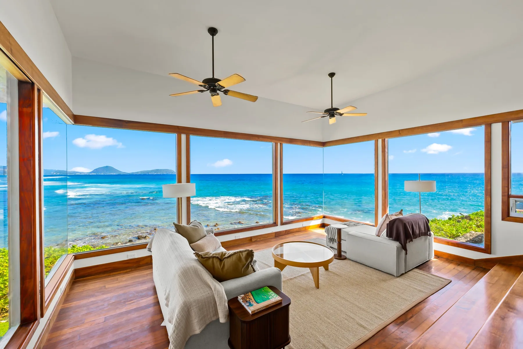 A living room with seating and large windows overlooking the ocean.