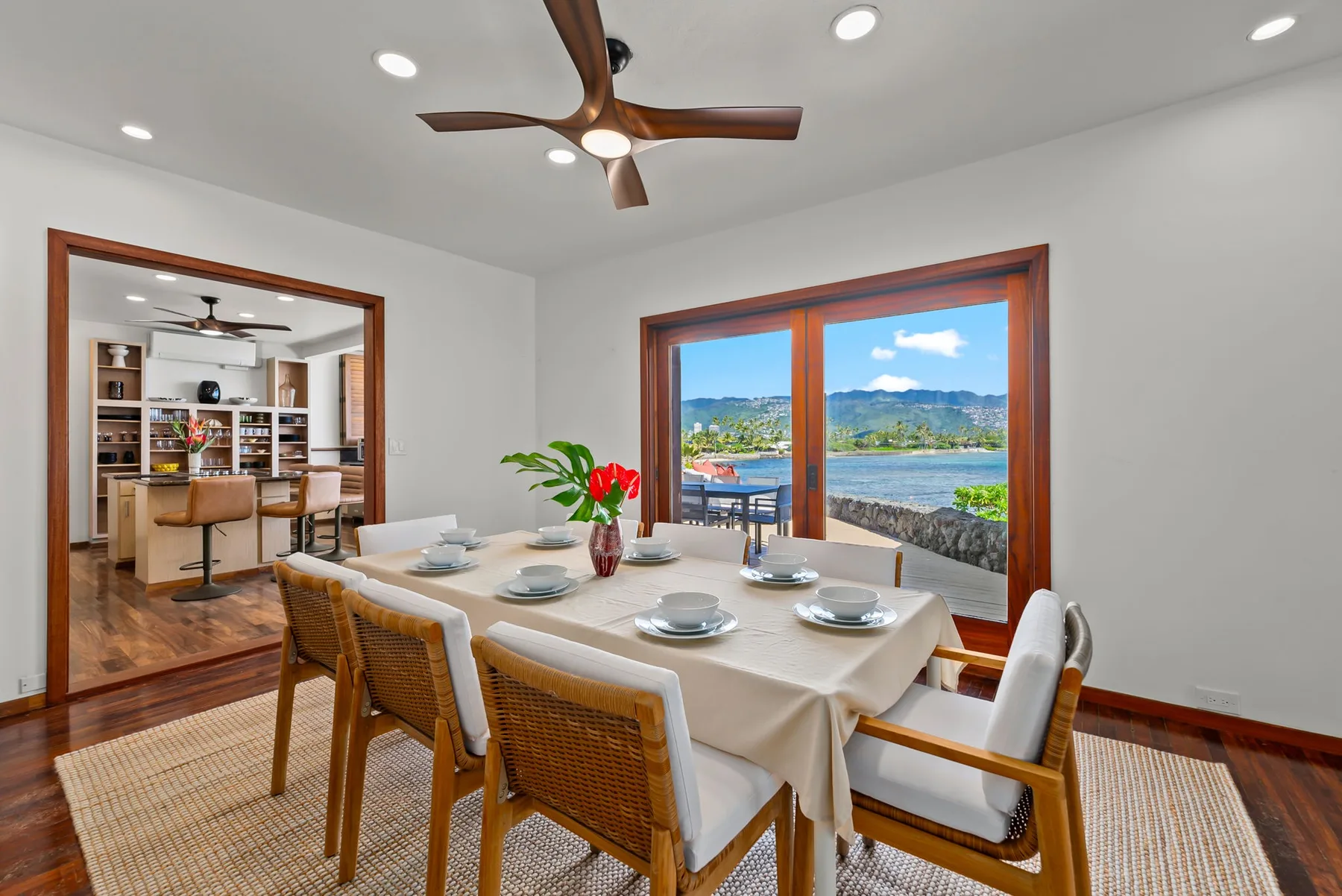 A dining area with a set table beside large windows overlooking the water.