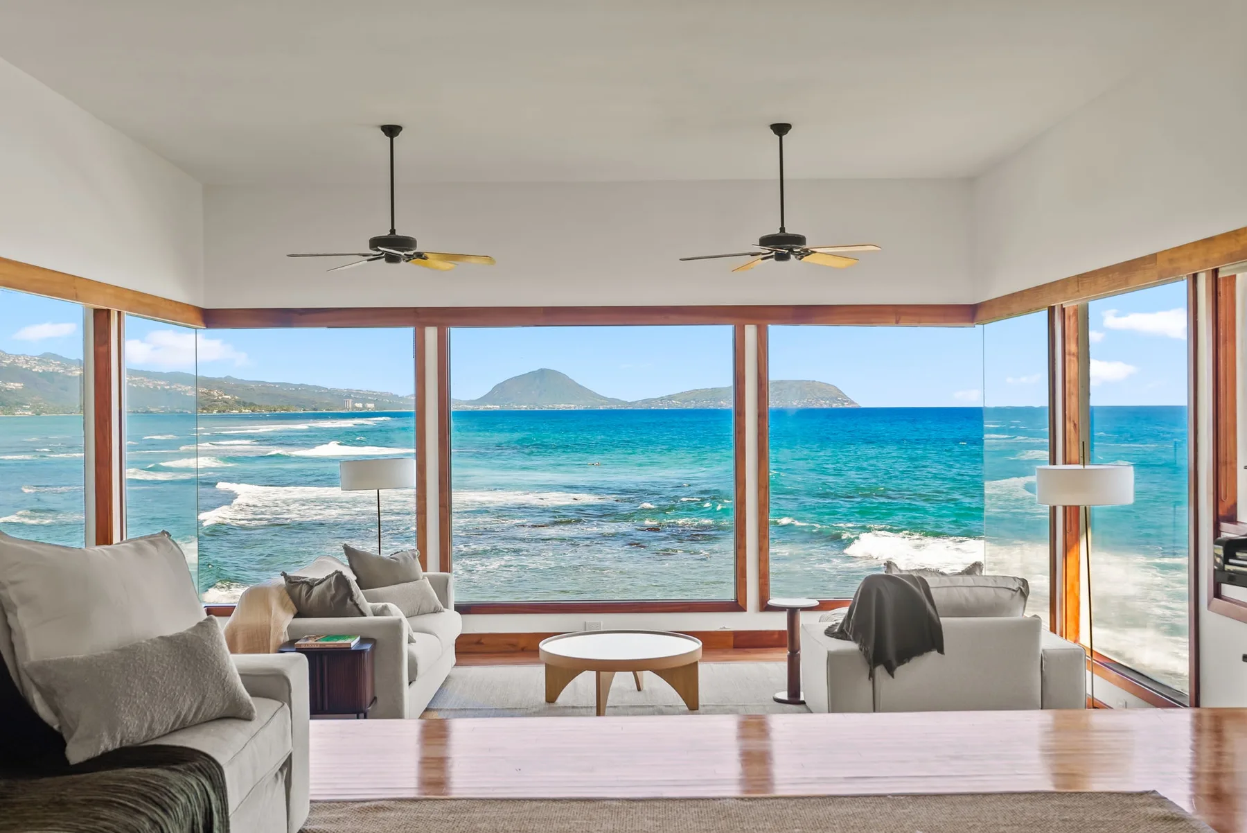 A bright living room with wide windows overlooking the ocean.