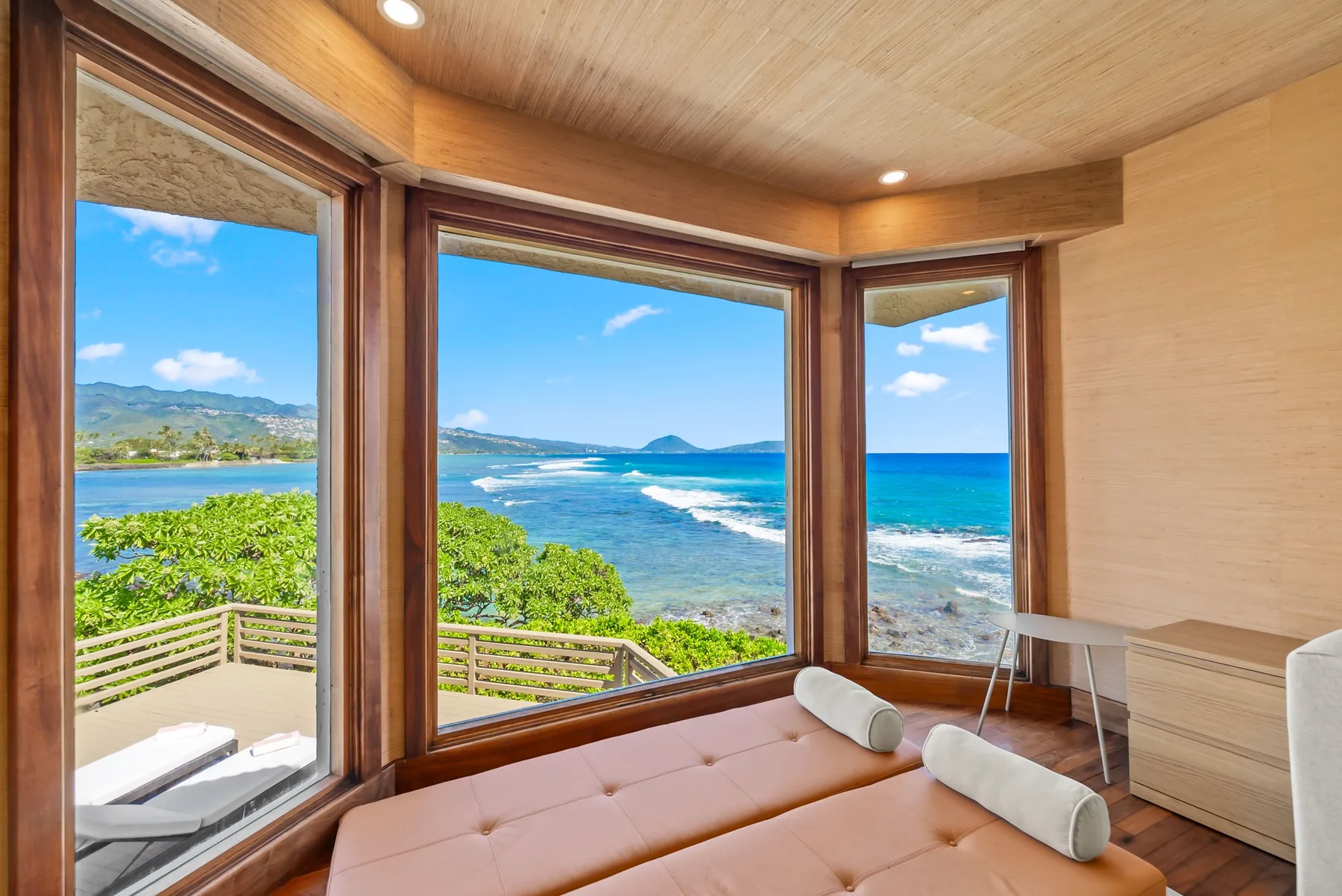 A room with large windows overlooking the ocean and a cushioned seating area.