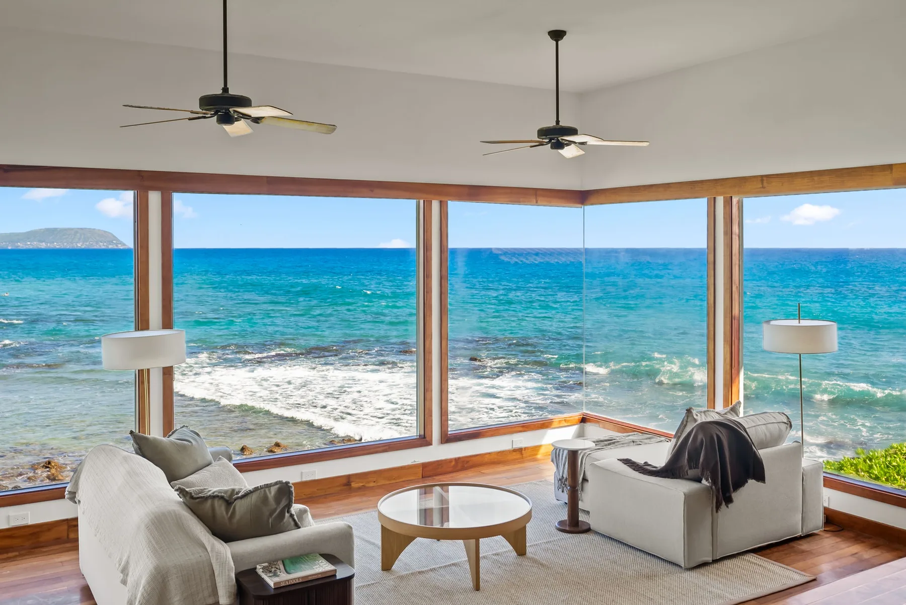 A living room with seating beside large windows overlooking the ocean.
