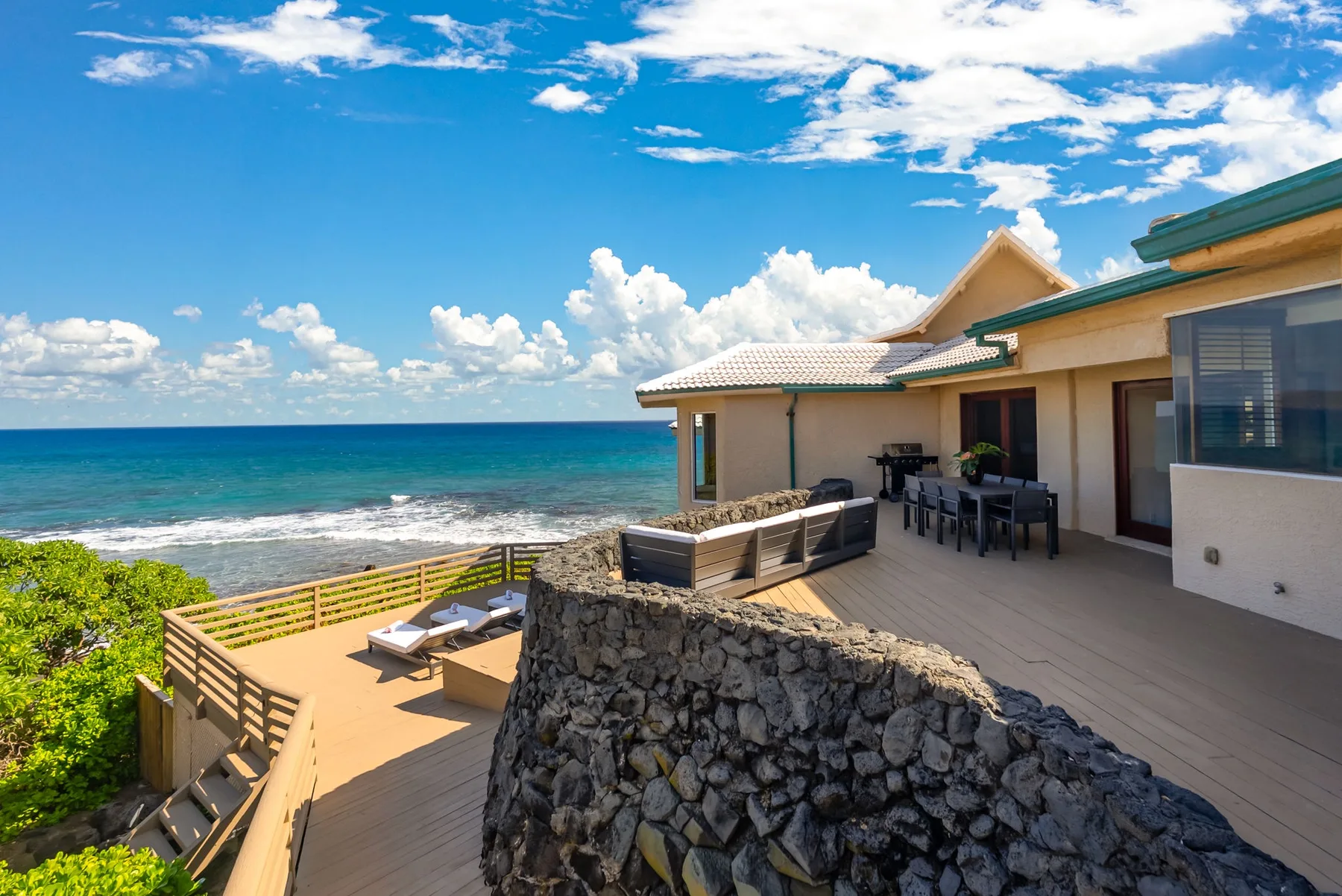 A seaside patio with outdoor seating overlooks the ocean.