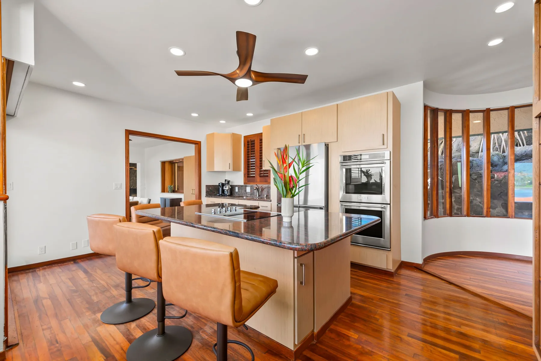 A bright kitchen with a central island, built-in appliances, and wood flooring.