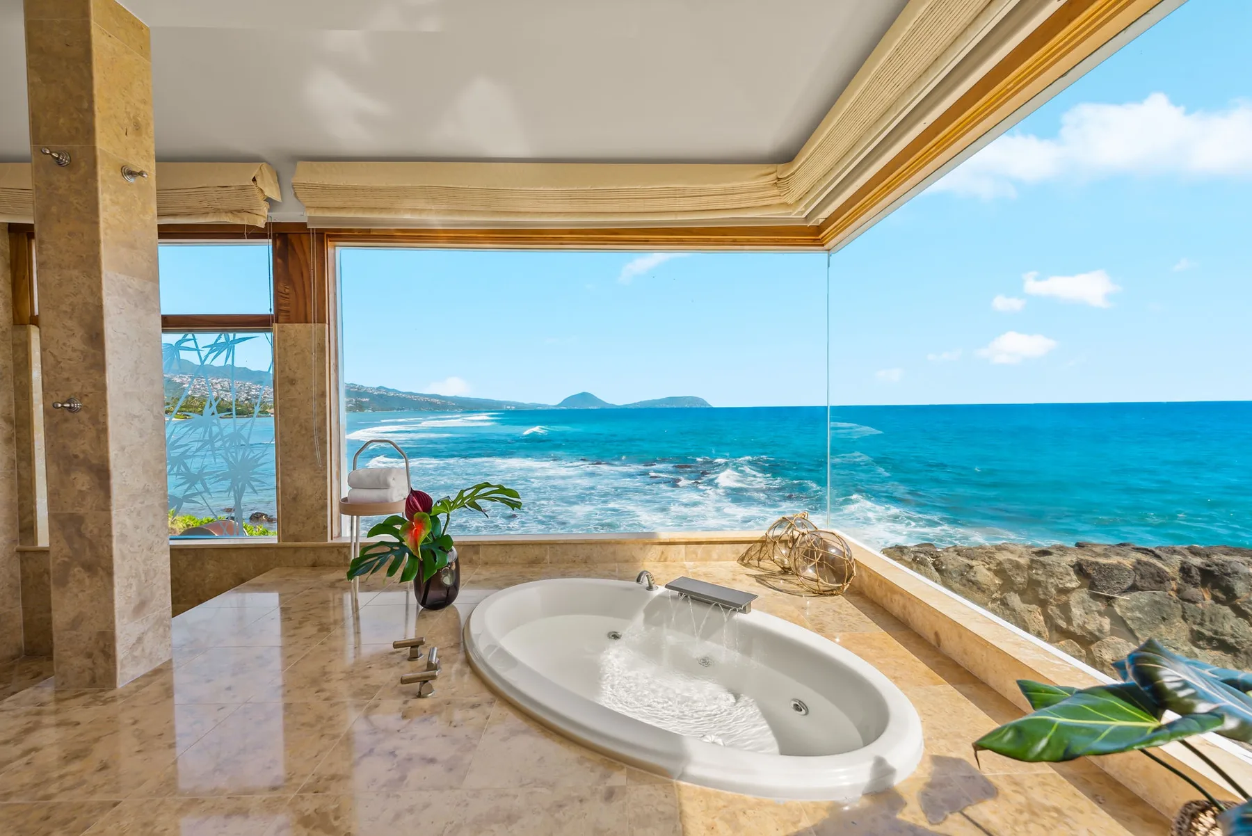 A seaside bathroom features a bathtub beside a broad window overlooking the ocean.