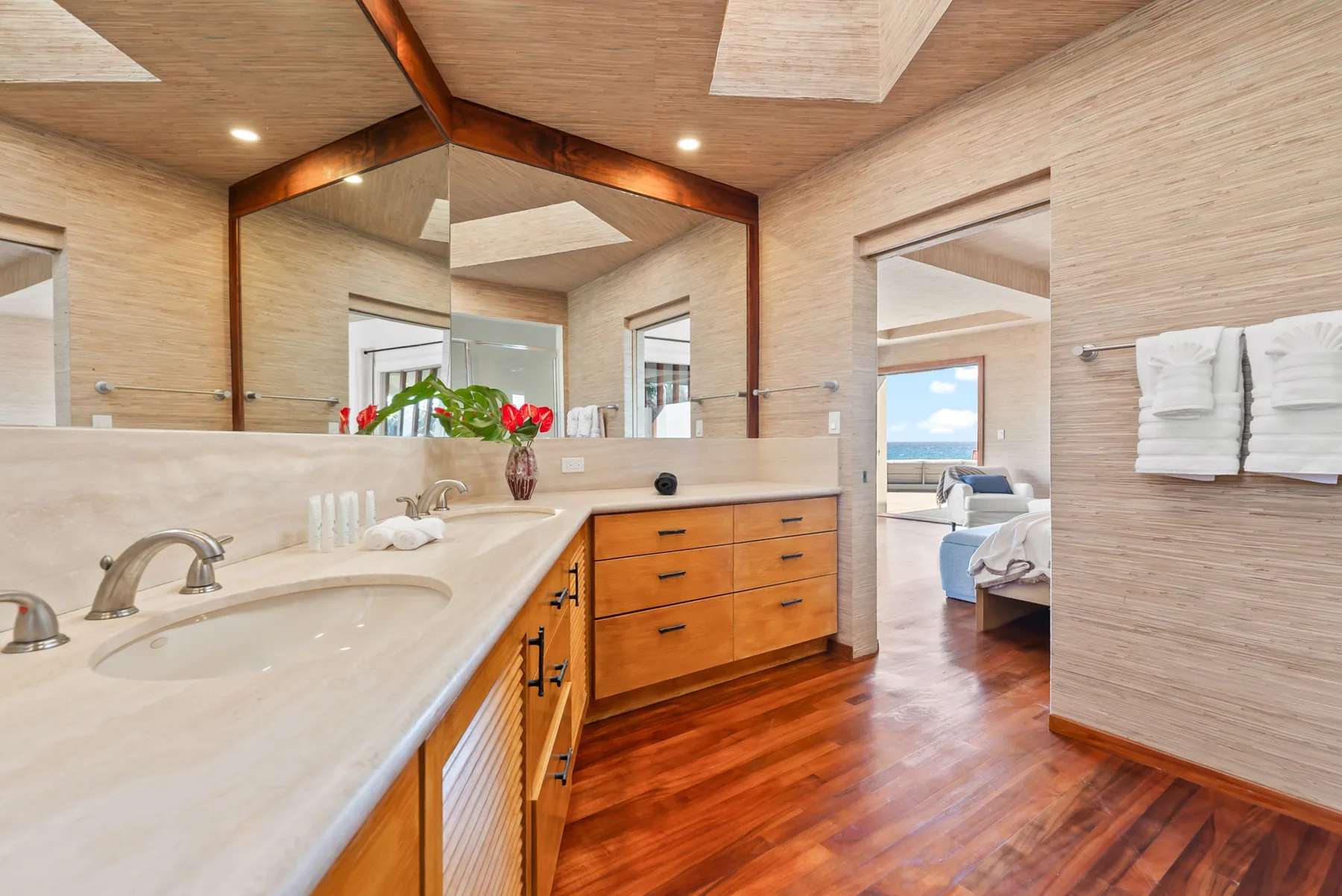 A spacious bathroom vanity opens onto a bedroom with a view of the water.