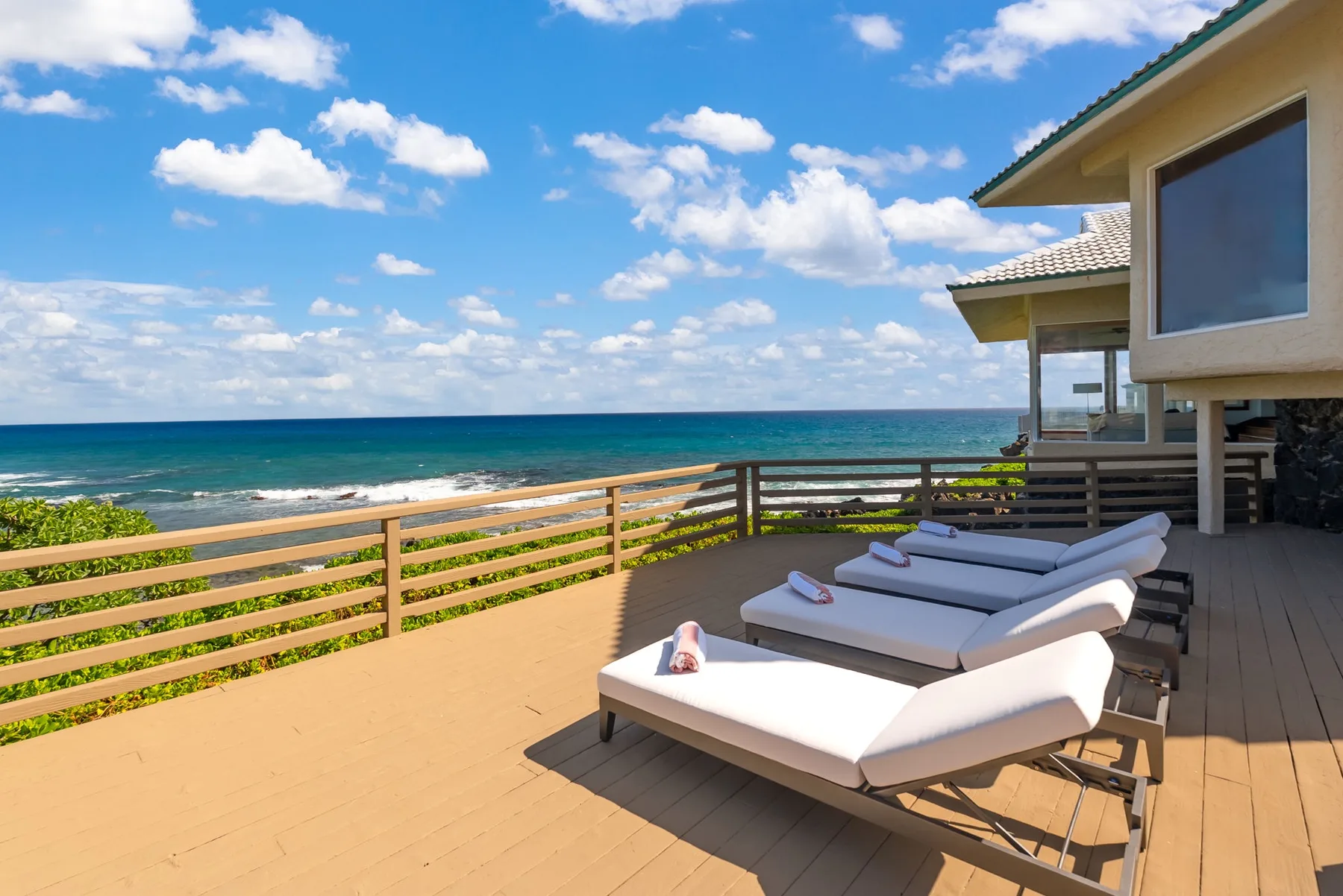 A seaside deck with lounge seating overlooks the ocean.