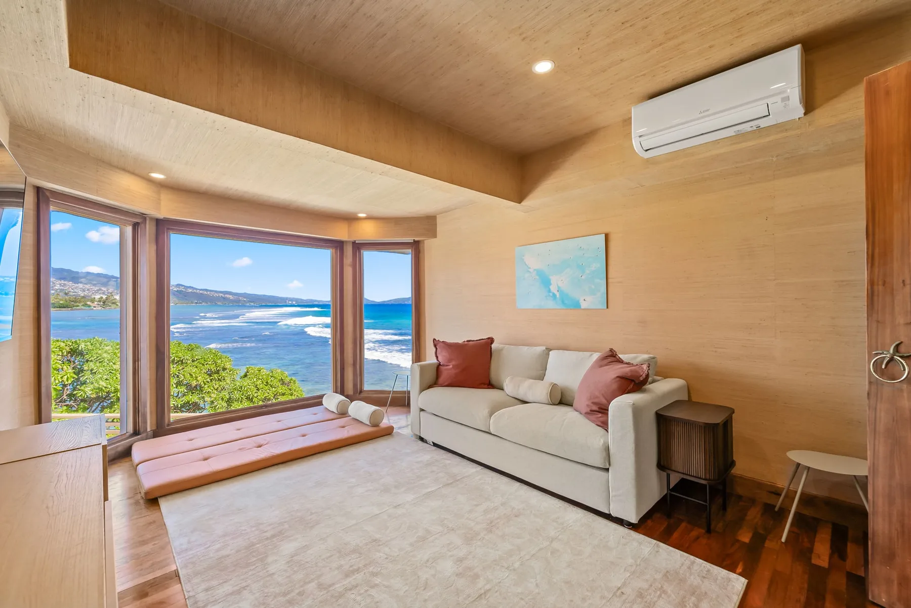 A living room with a light sofa beside large windows overlooking the coast.