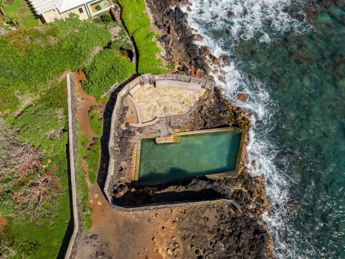 Aerial view of a seaside swimming pool set into a rocky coastline.