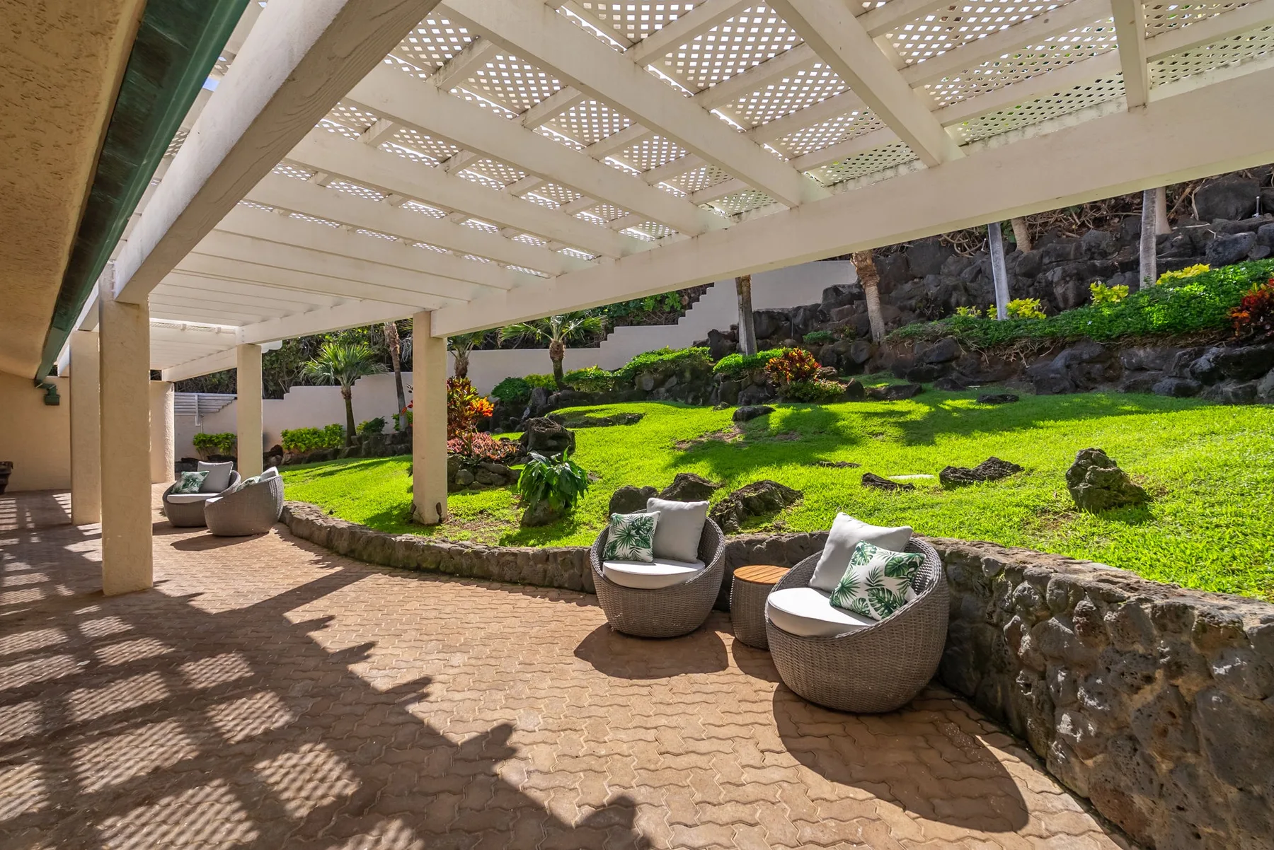 A covered patio with outdoor seating overlooks a landscaped garden.