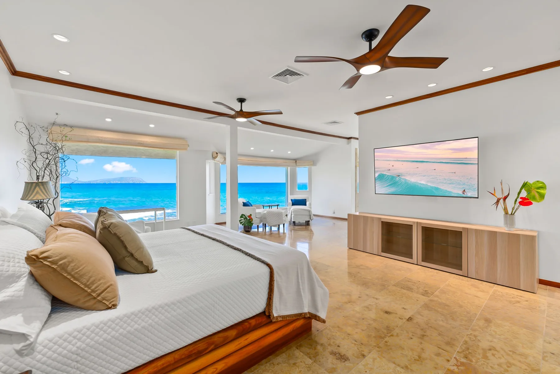 A bright bedroom with a bed, ocean views, and a dining area.