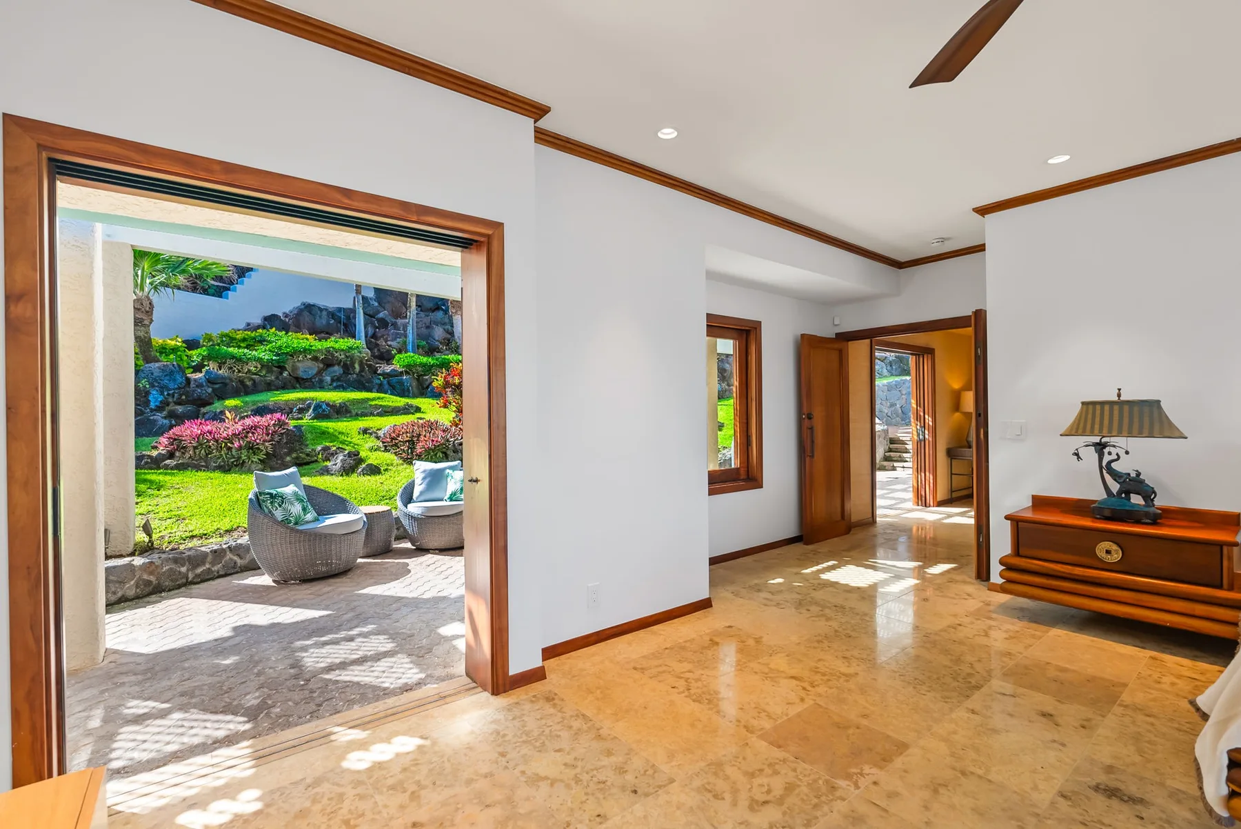 A bright interior opens onto a garden patio, with polished stone flooring.