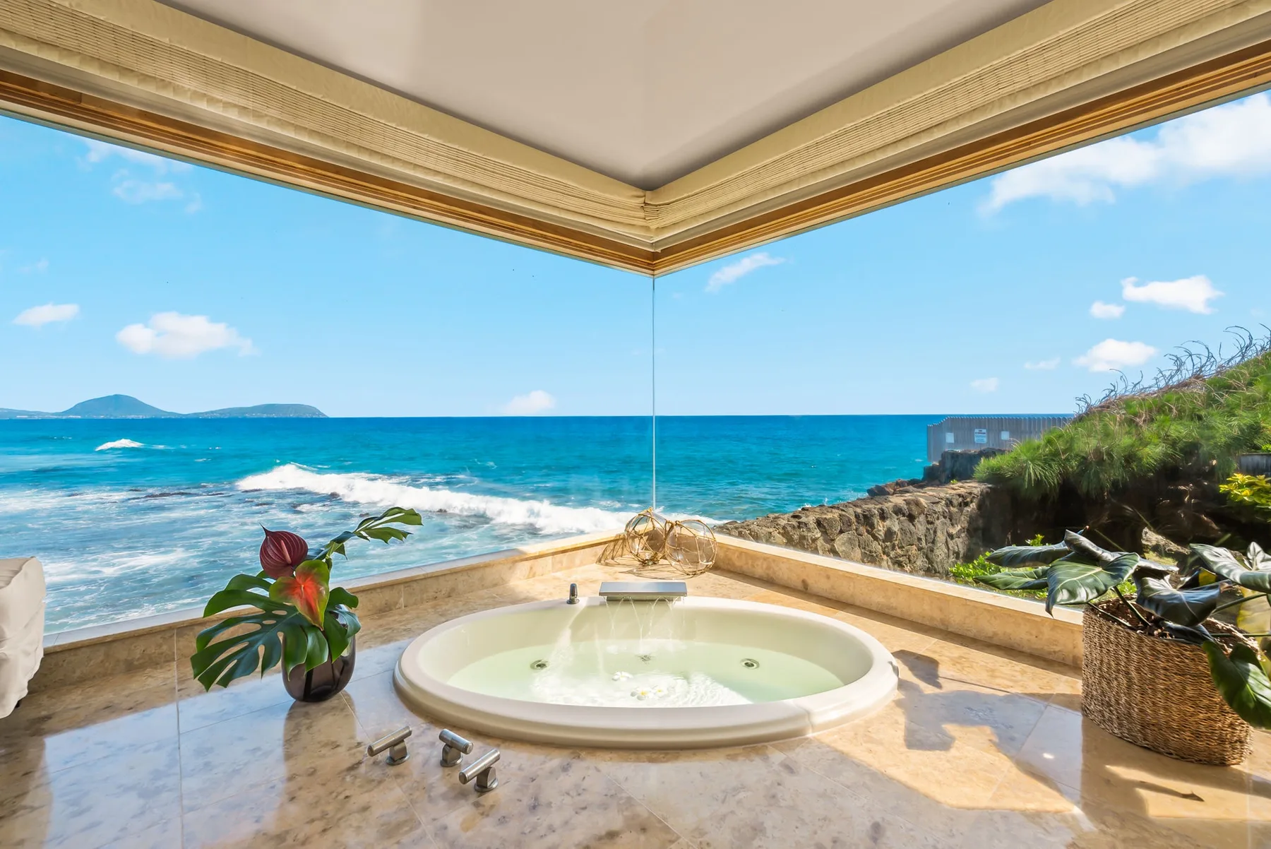 A seaside terrace features a round soaking tub overlooking the ocean.