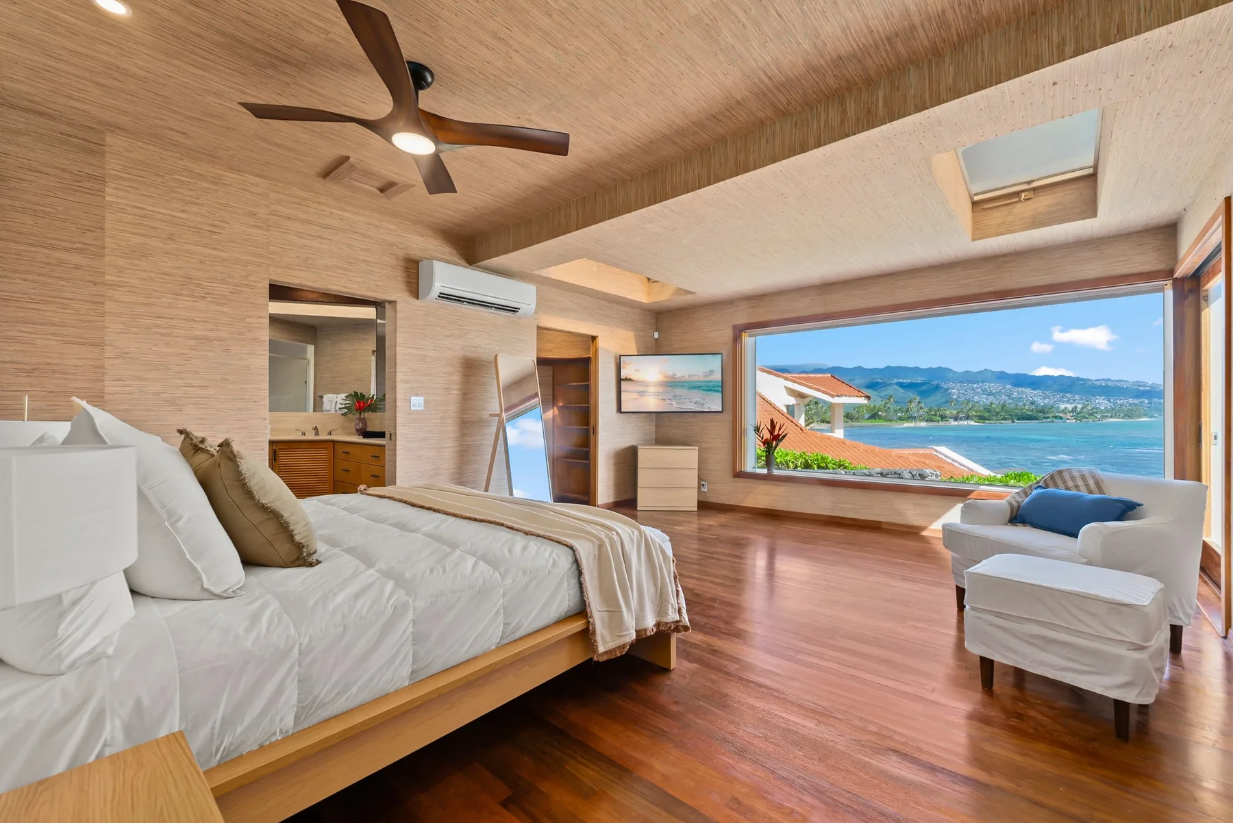 A bedroom with a large window overlooking the water and surrounding landscape.