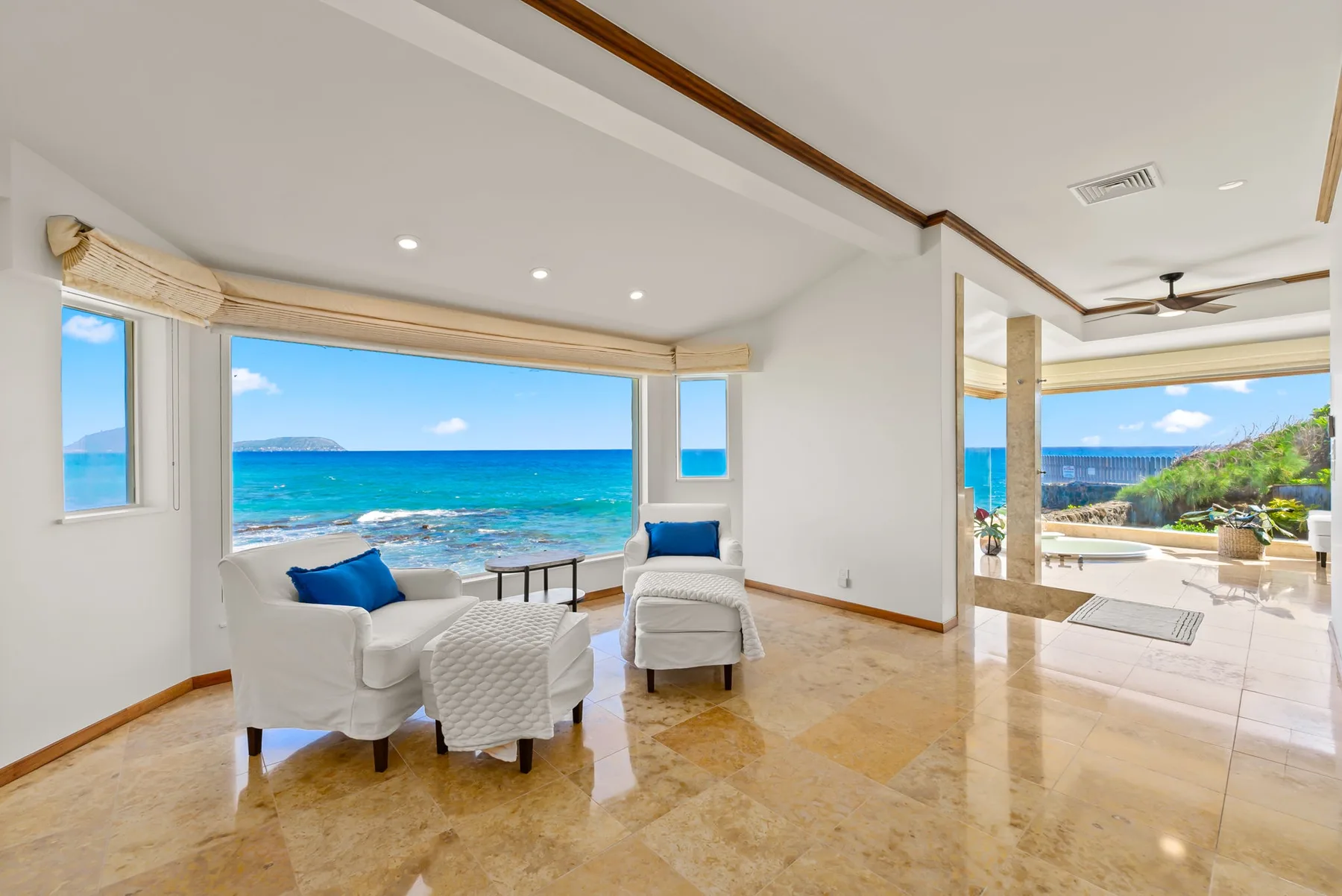 A bright living area with seating faces large windows overlooking the ocean.