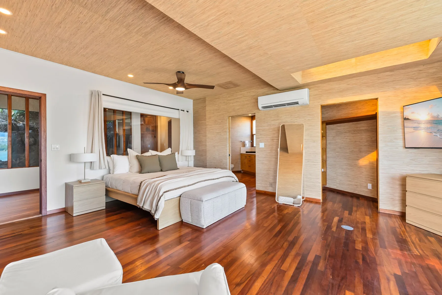 A bedroom with a bed, a ceiling fan, and wood flooring.