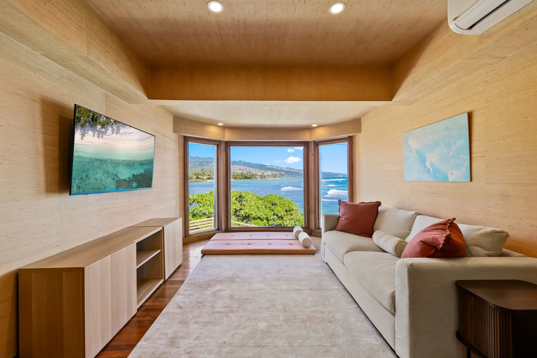 A bright living room with a sofa and wide windows overlooking the water.
