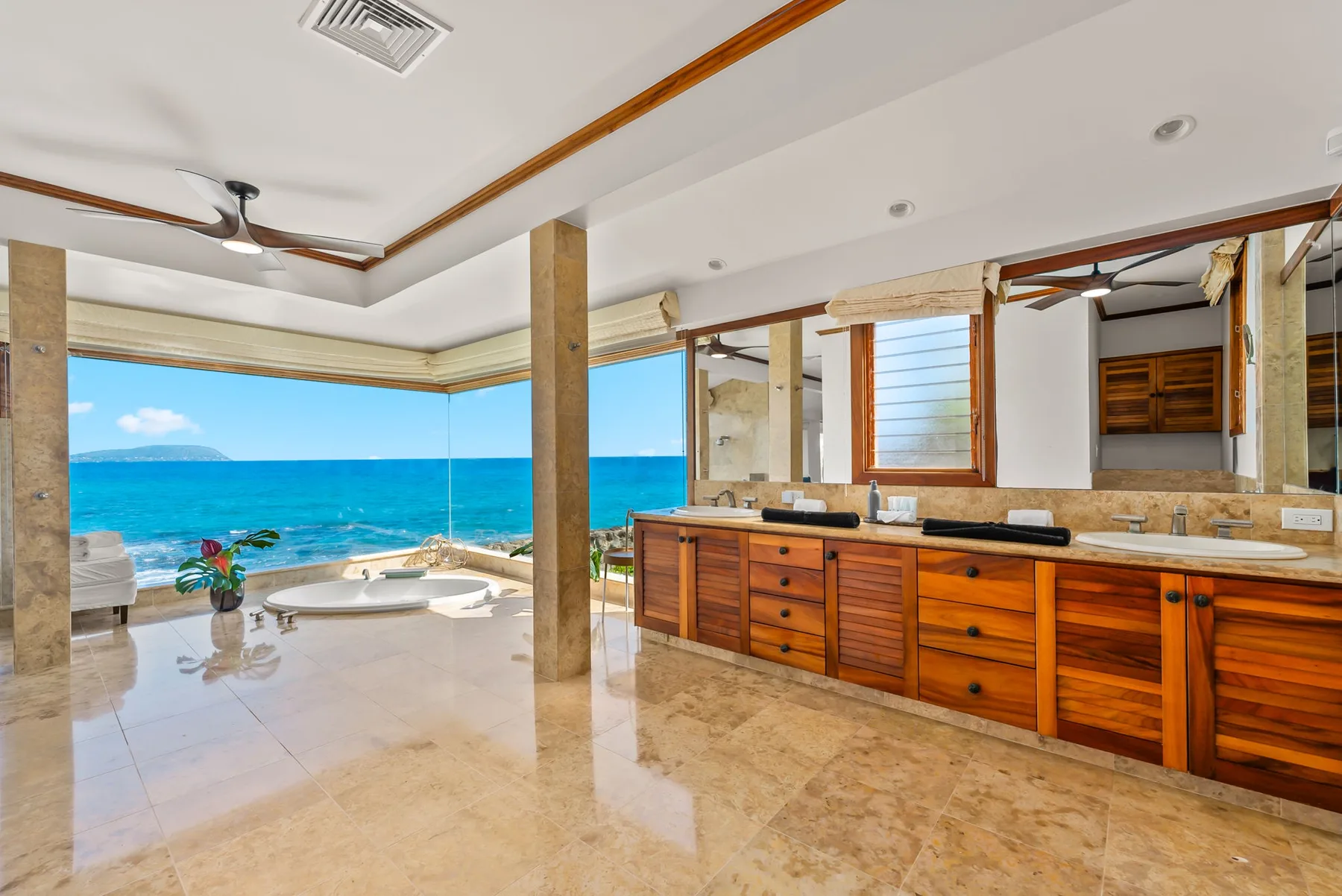 A bathroom with a long wooden vanity and a wide ocean view.