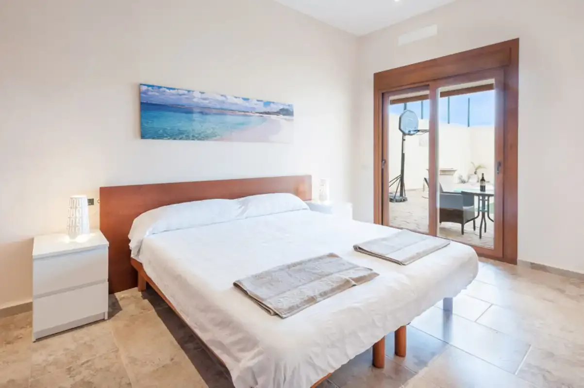Un dormitorio luminoso con una cama bien hecha y puertas de cristal.