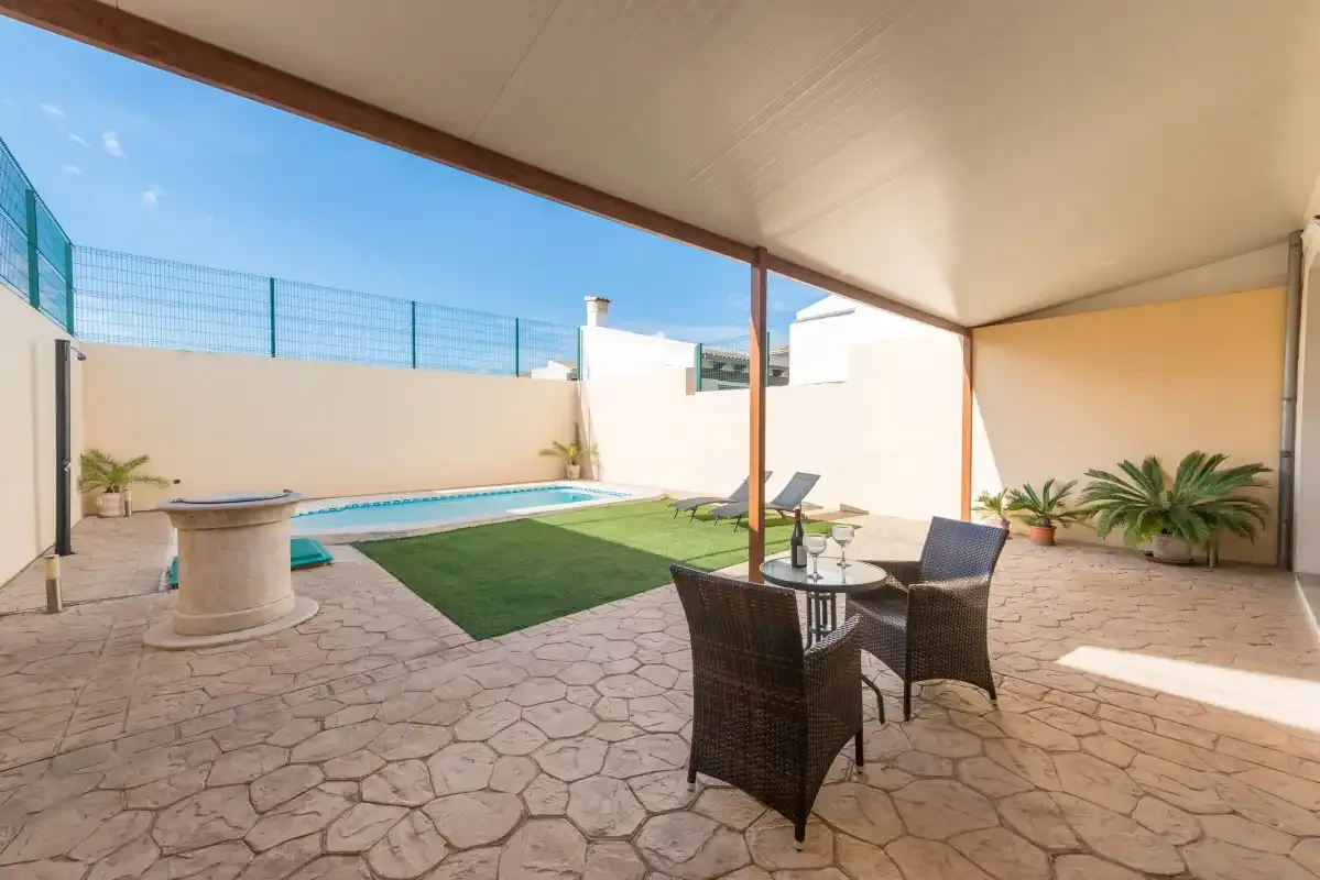 Un patio cubierto con asientos al aire libre da a una pequeña piscina.