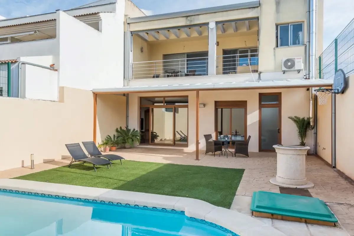 Patio junto a la piscina con asientos al aire libre y un pequeño césped.