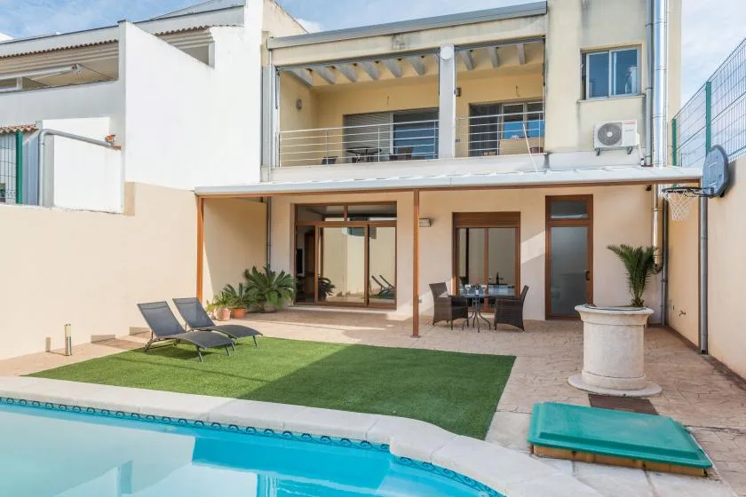 A courtyard patio with a swimming pool, lawn, and outdoor seating.