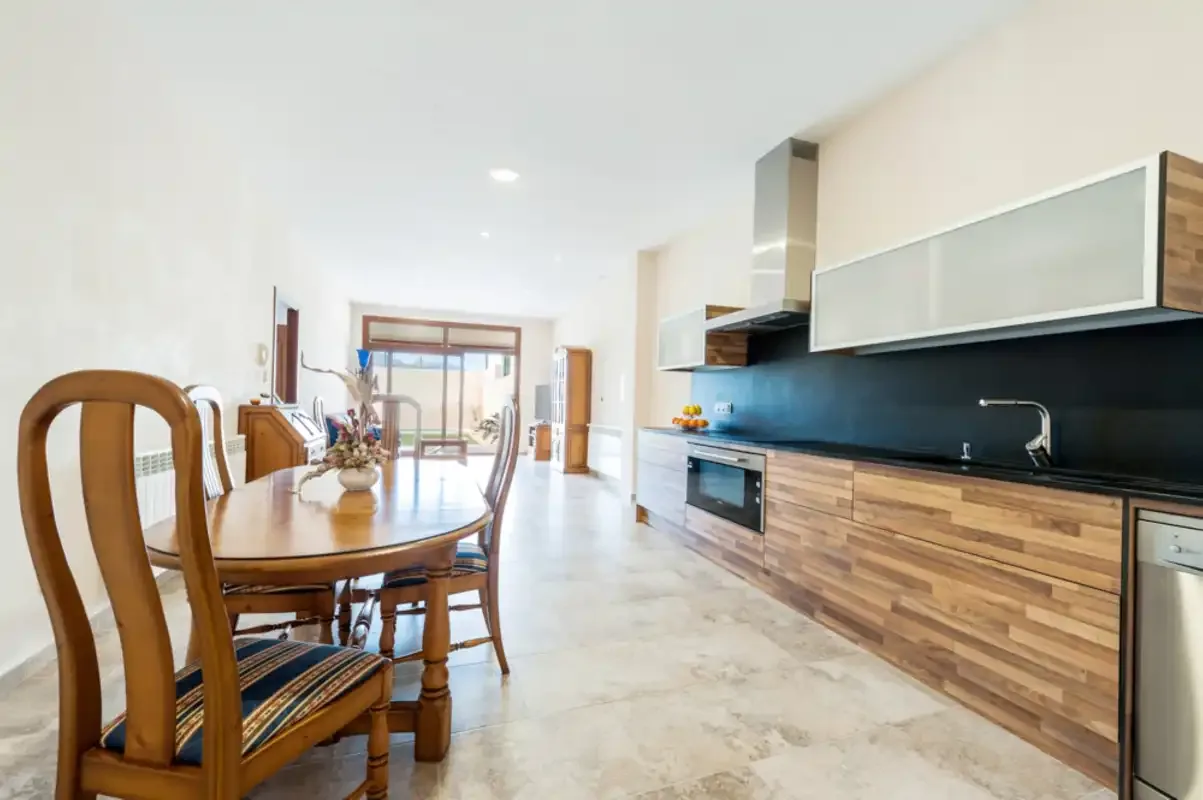 Una cocina y comedor de planta abierta, luminosos, con mesa y sillas de madera.